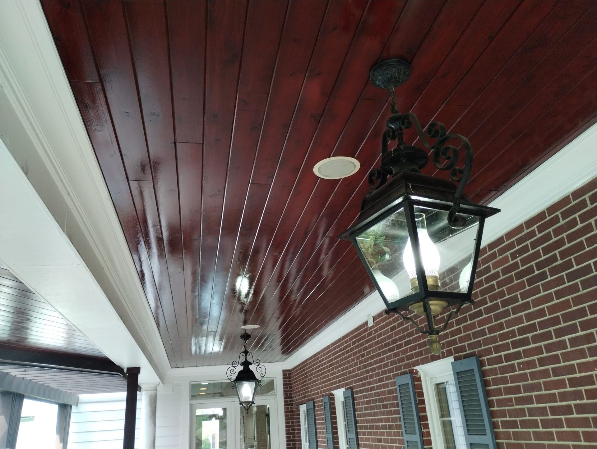 Wooden porch ceiling with ornate light fixtures against red brick.