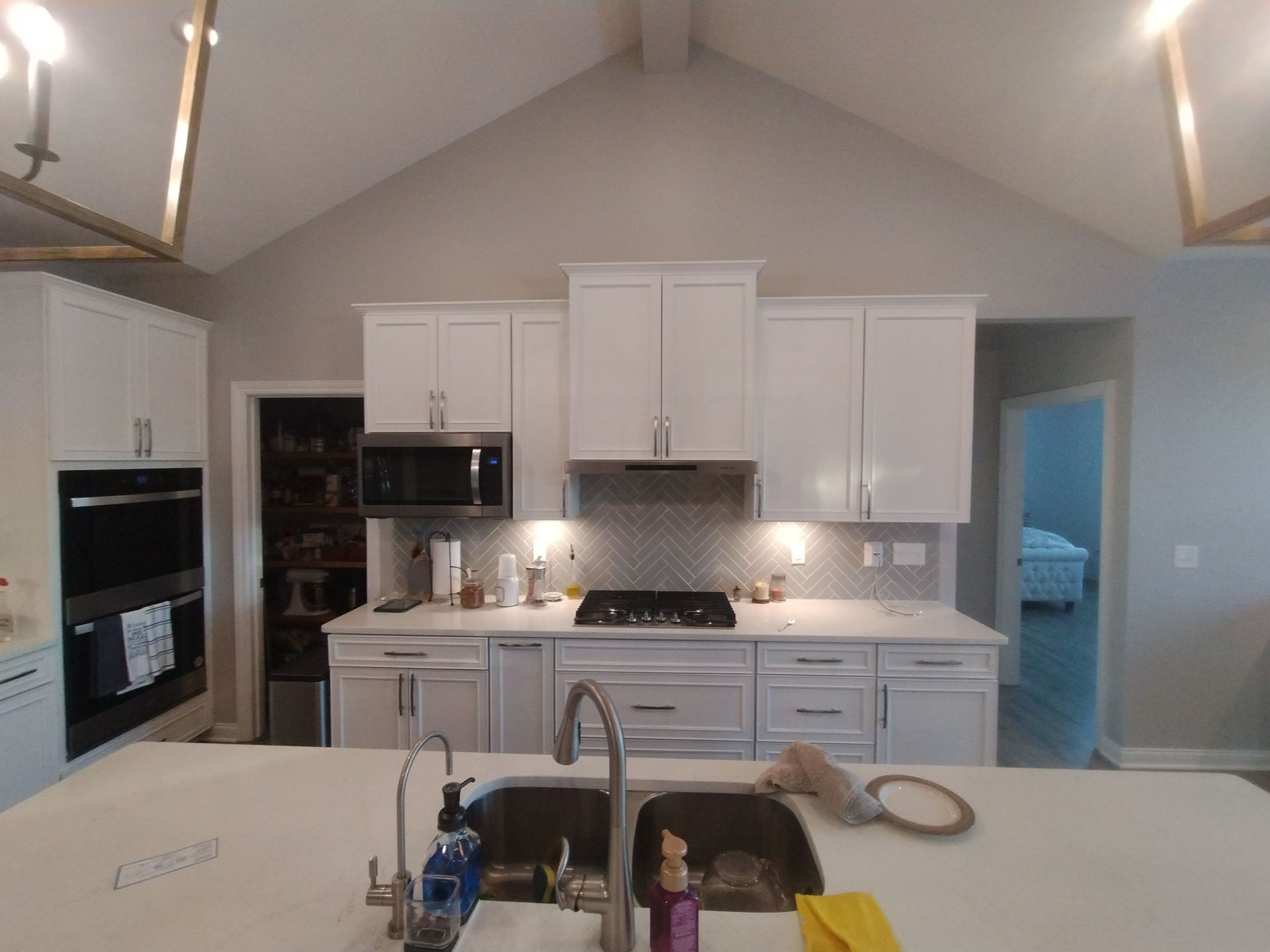 White kitchen with island, cabinets, appliances, and a vaulted ceiling.