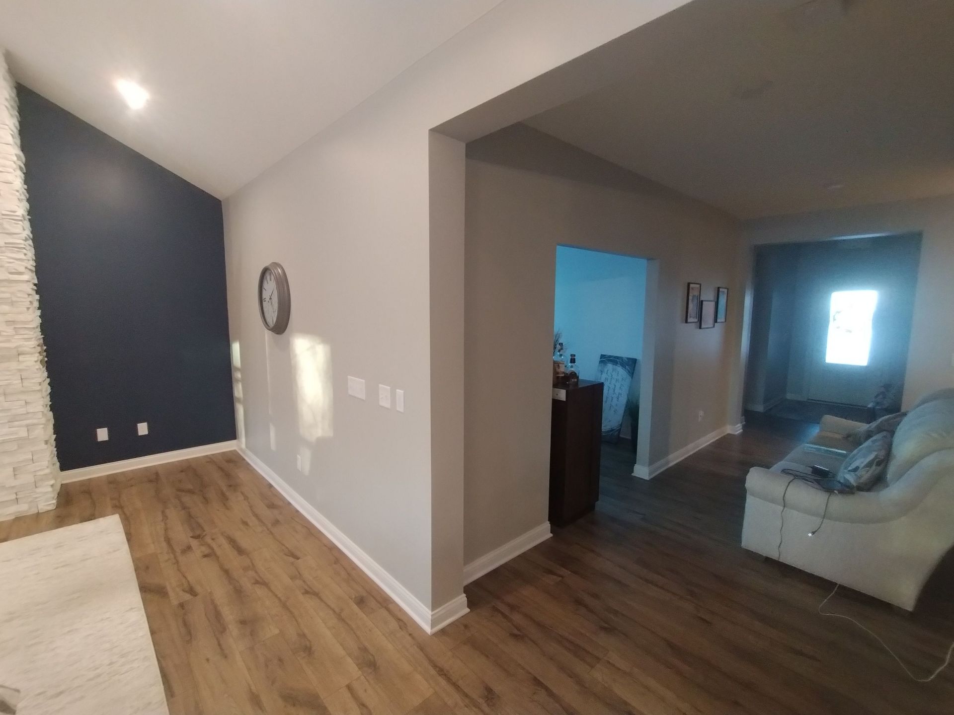 A living room with a couch and a clock on the wall.
