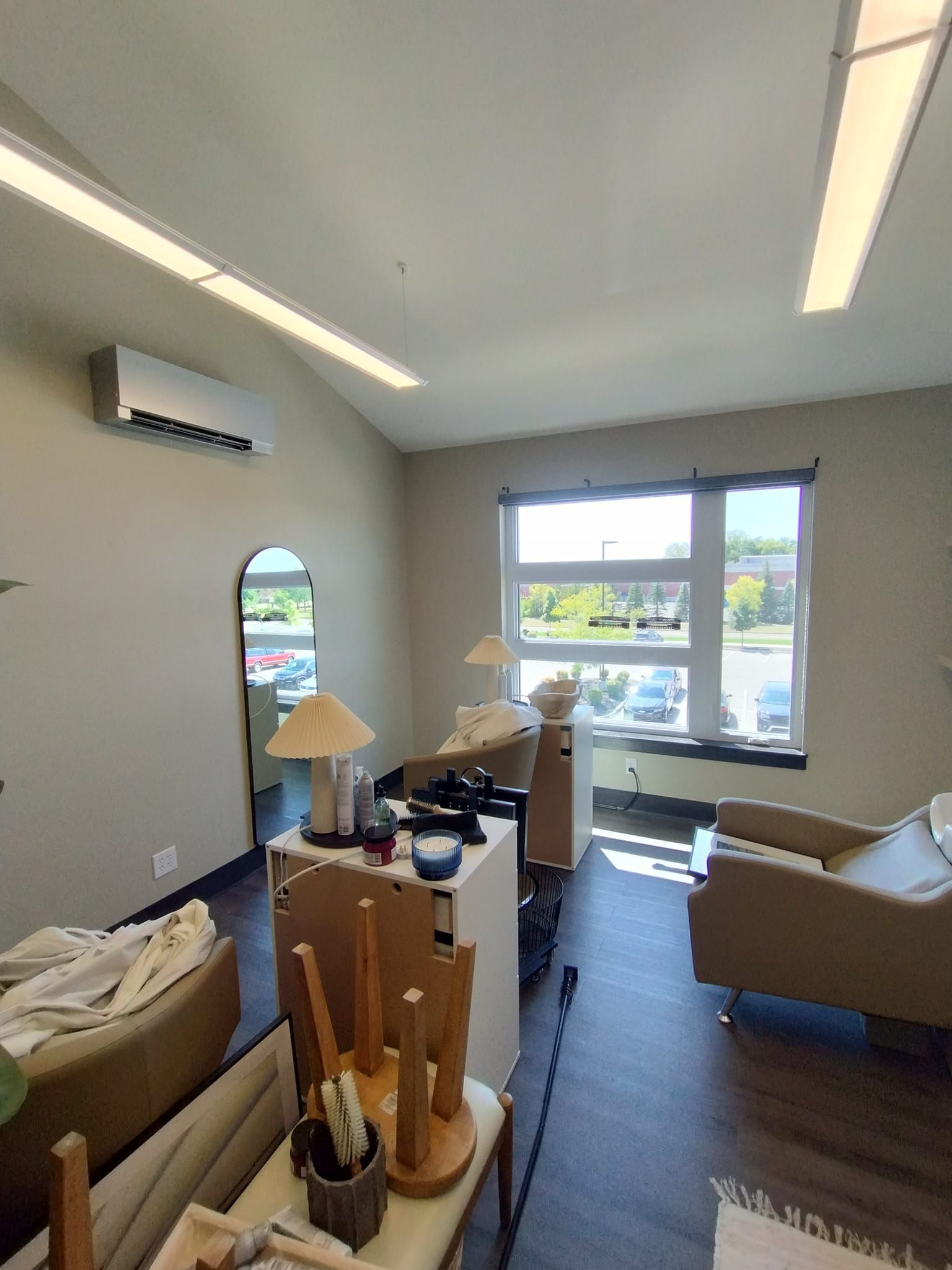 A living room with a couch , chair , table , mirror and air conditioner.