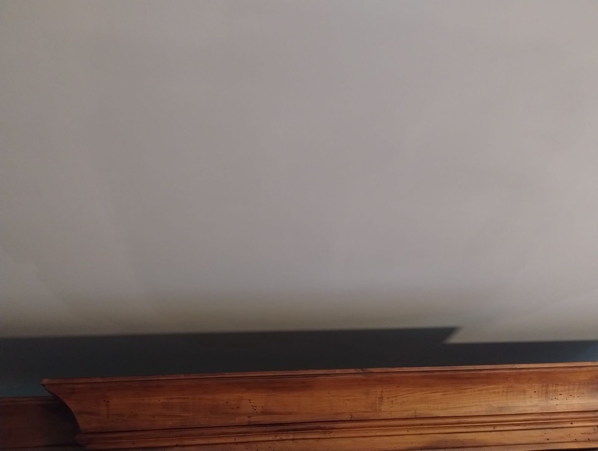 Brown wooden trim below a white ceiling with a shadow.