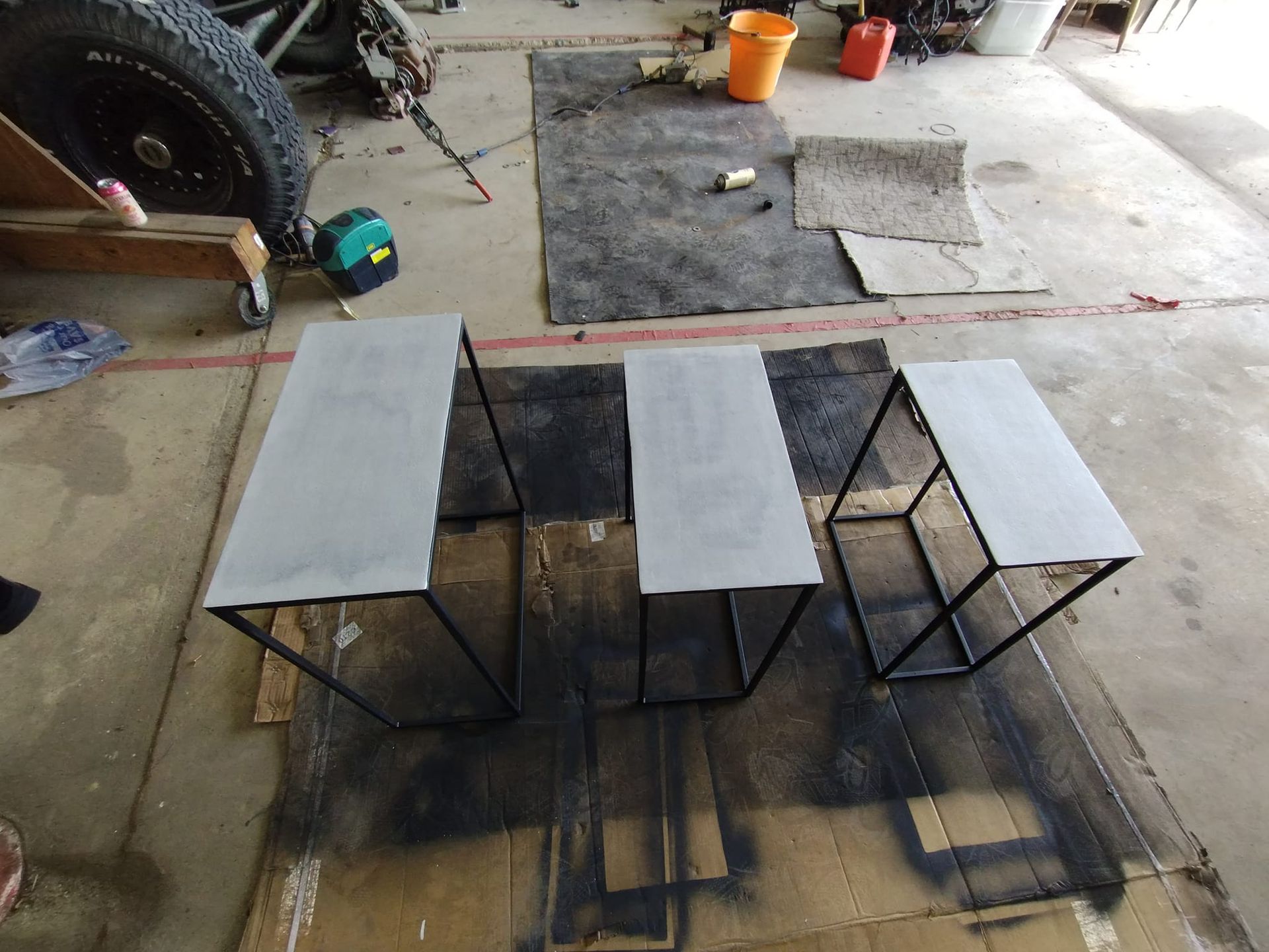 White wall with air vent, black pipe, wood beam ceiling, cabinets, and a hanging lampshade.