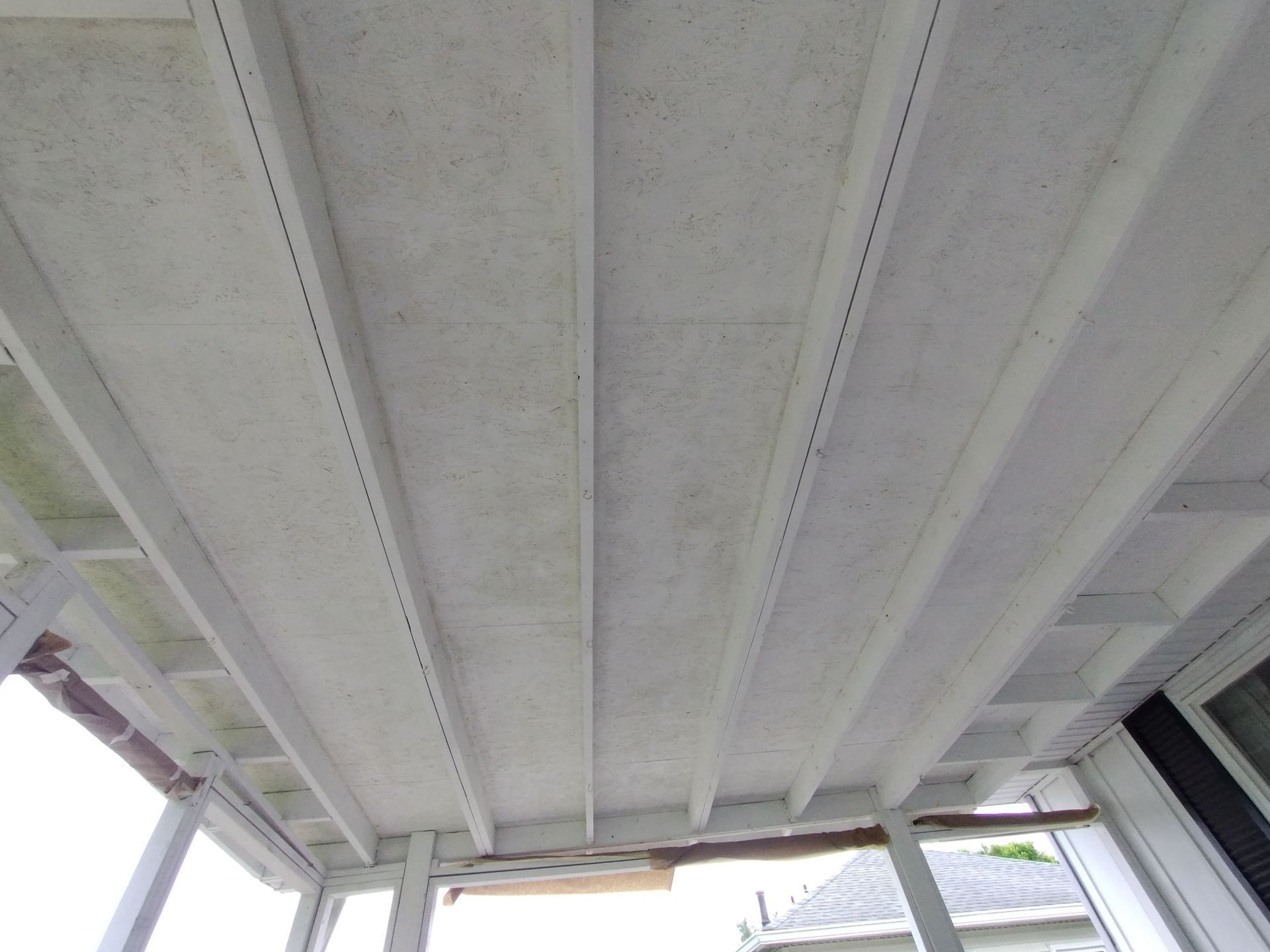 White porch ceiling with beams, seen from below.