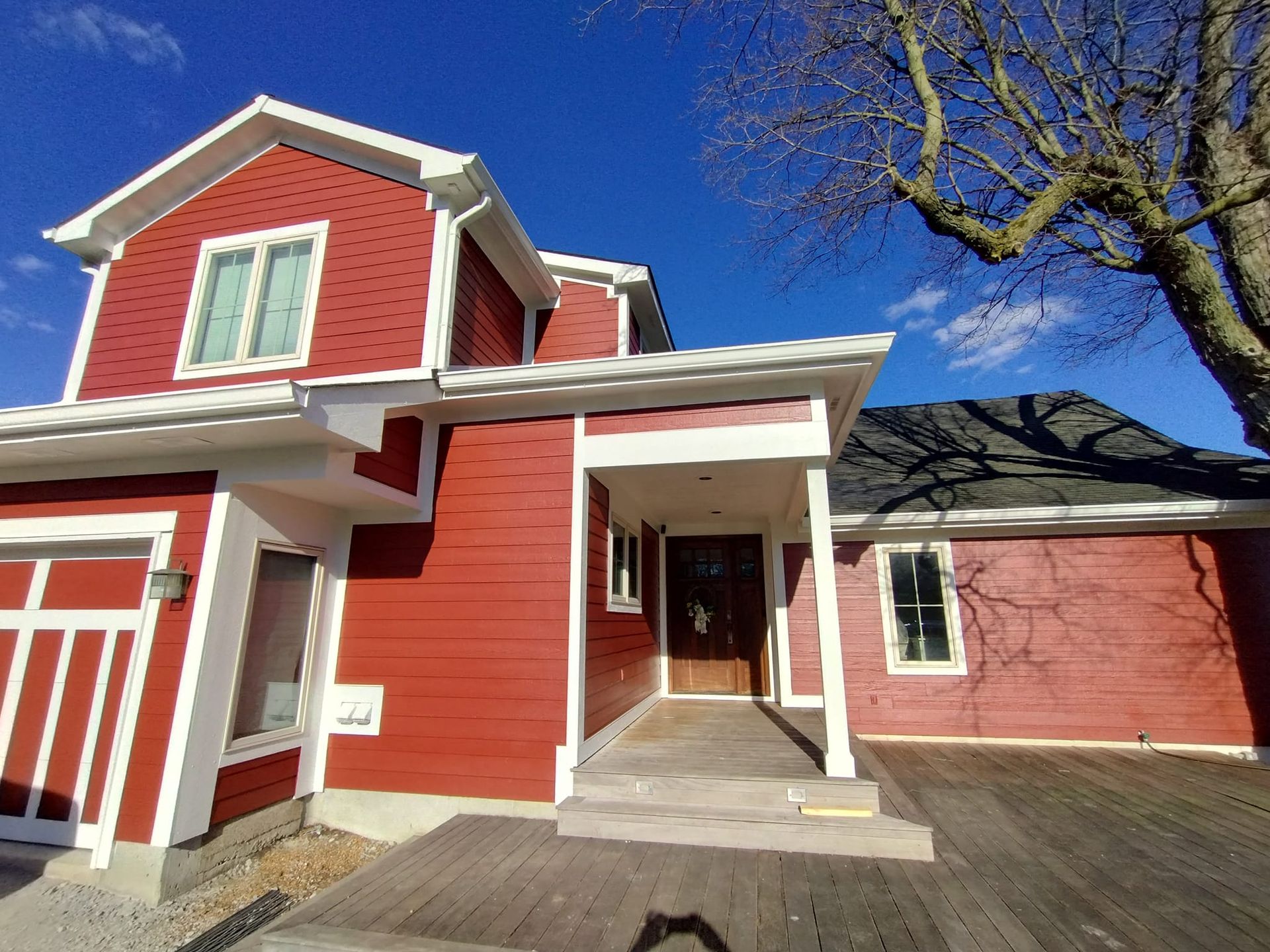 A red house with white trim and a blue sky in the background