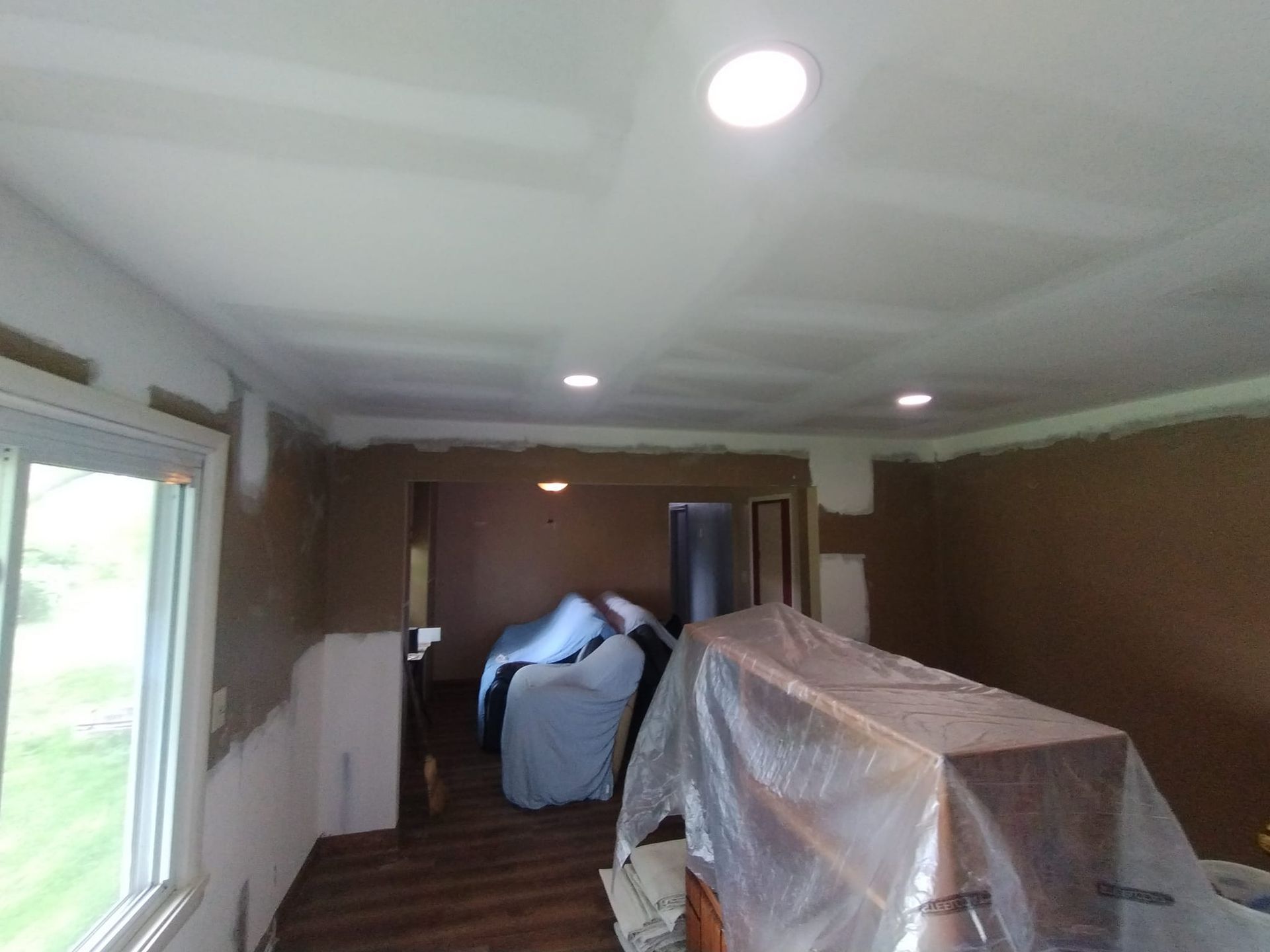 A living room with a couch and a table covered in plastic.