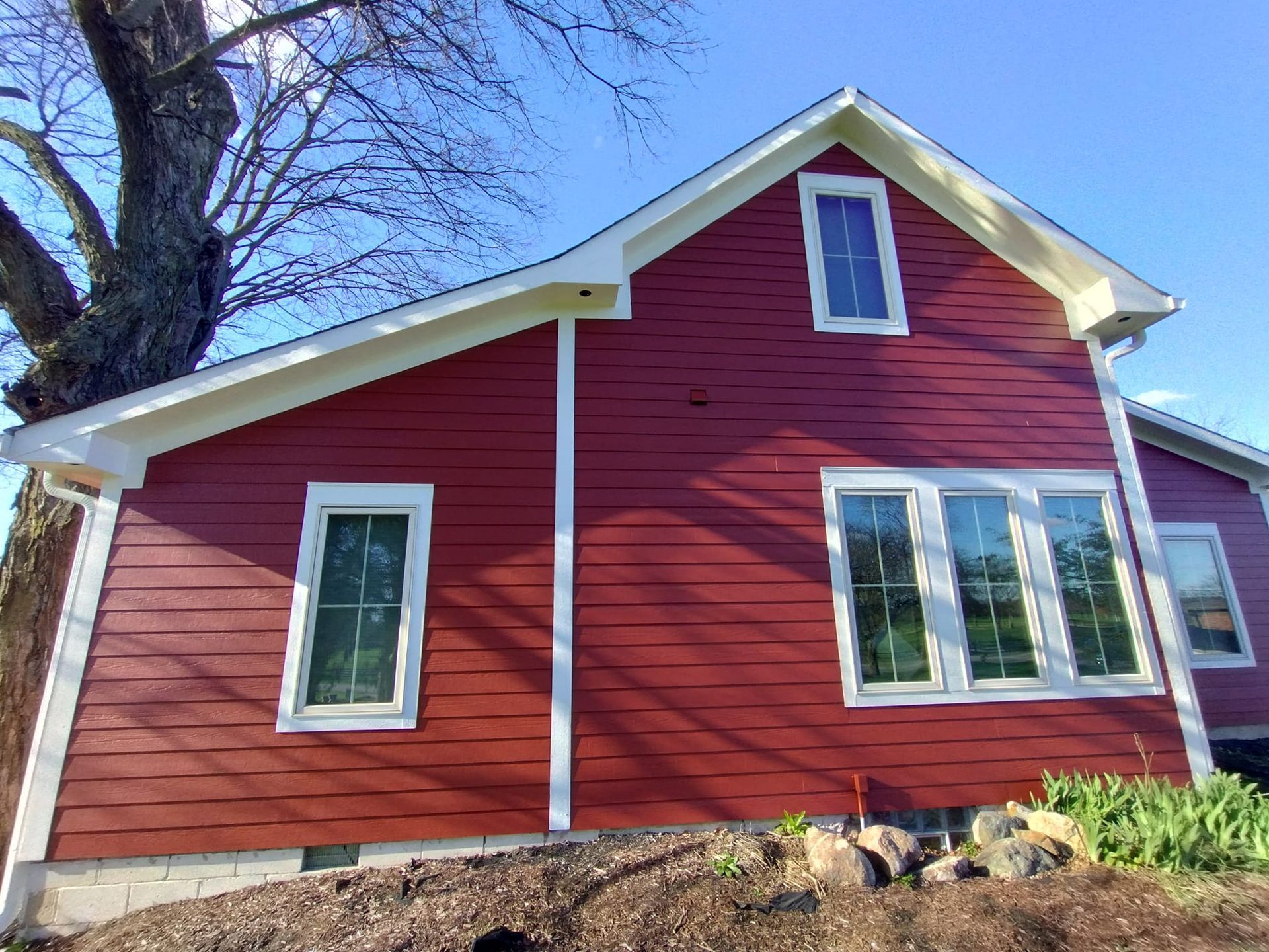 A red house with white trim and a tree in the background