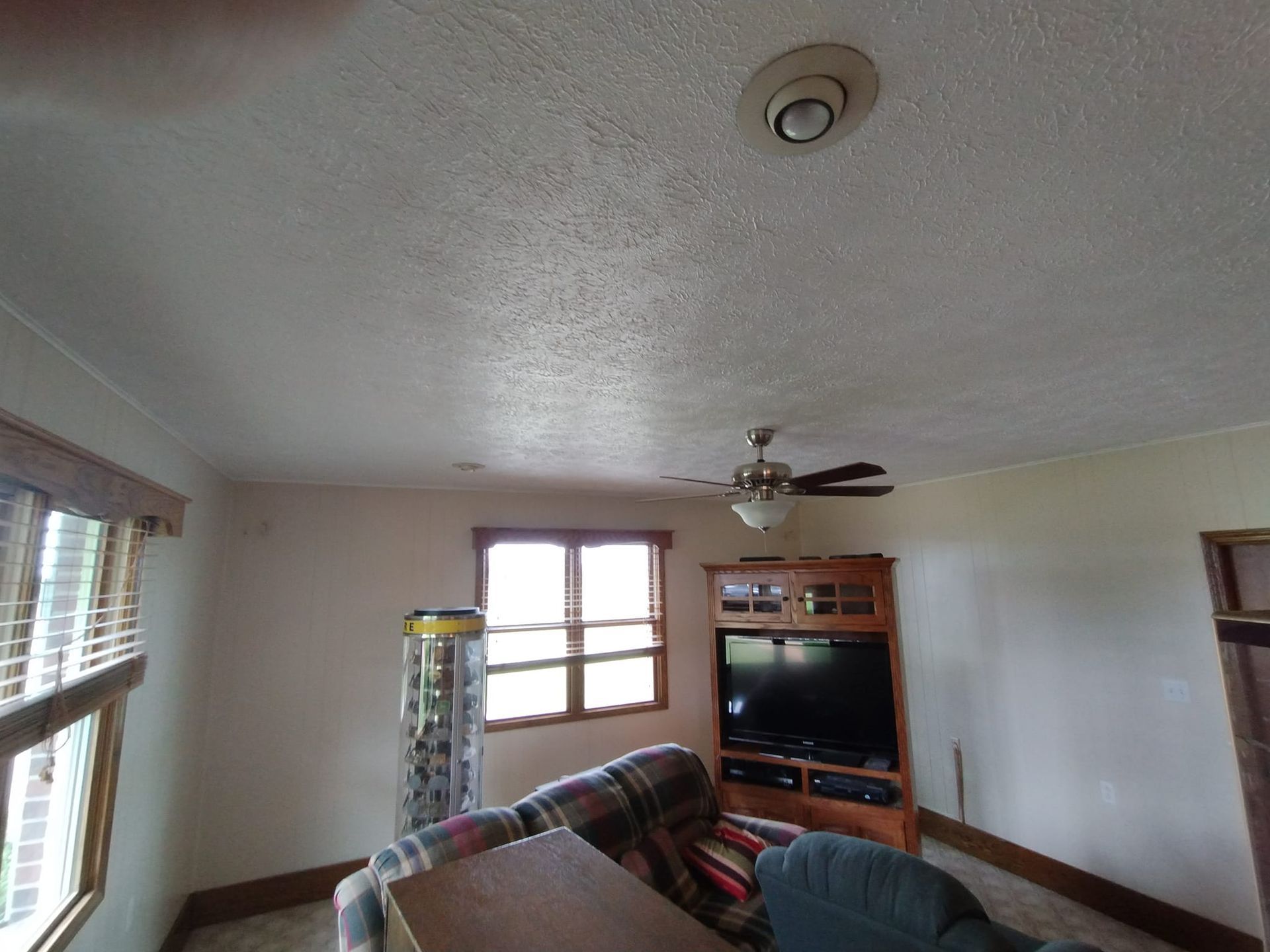 A living room with a ceiling fan and a flat screen tv