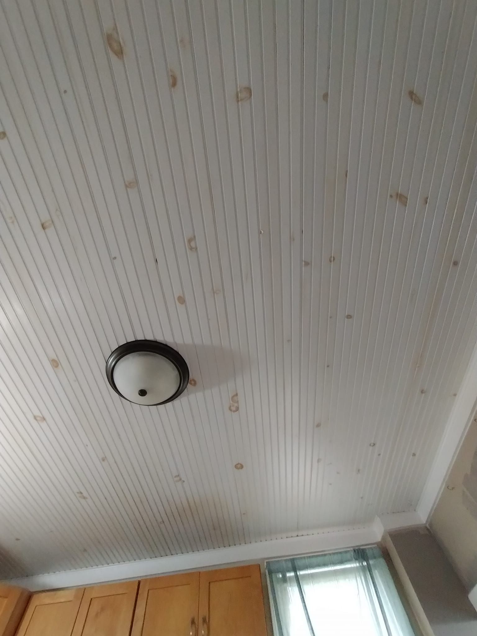 A kitchen with a white ceiling and a light on it.