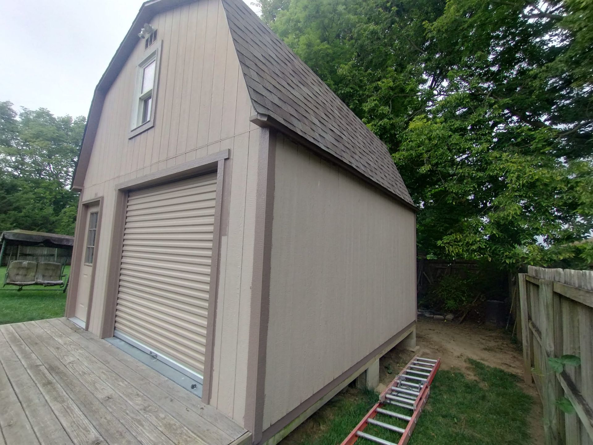 A small barn with a ladder in front of it.