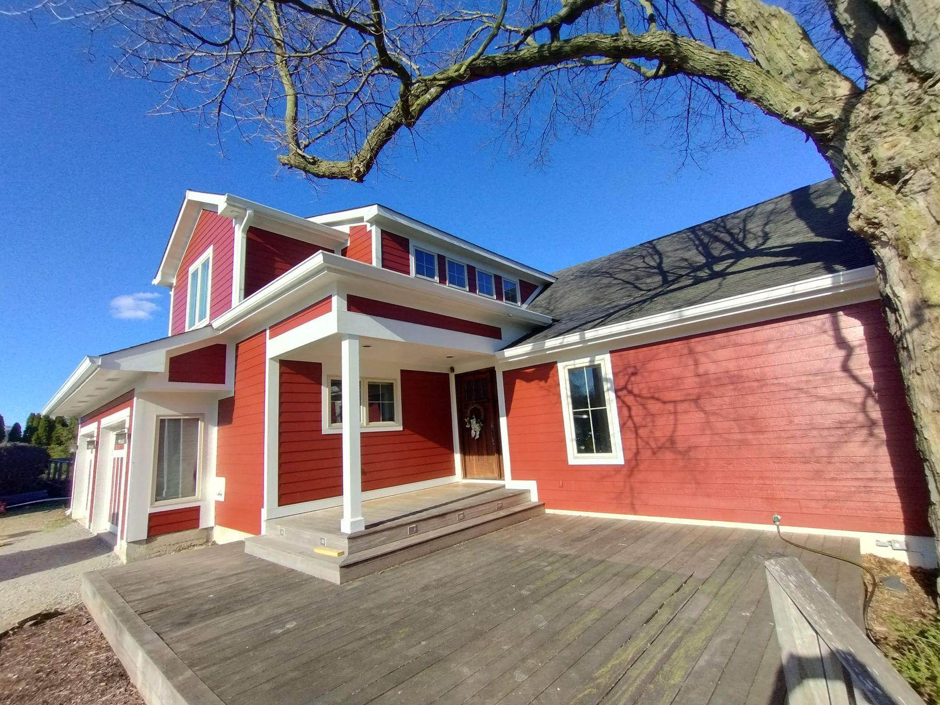A large red house with a porch and a tree in front of it