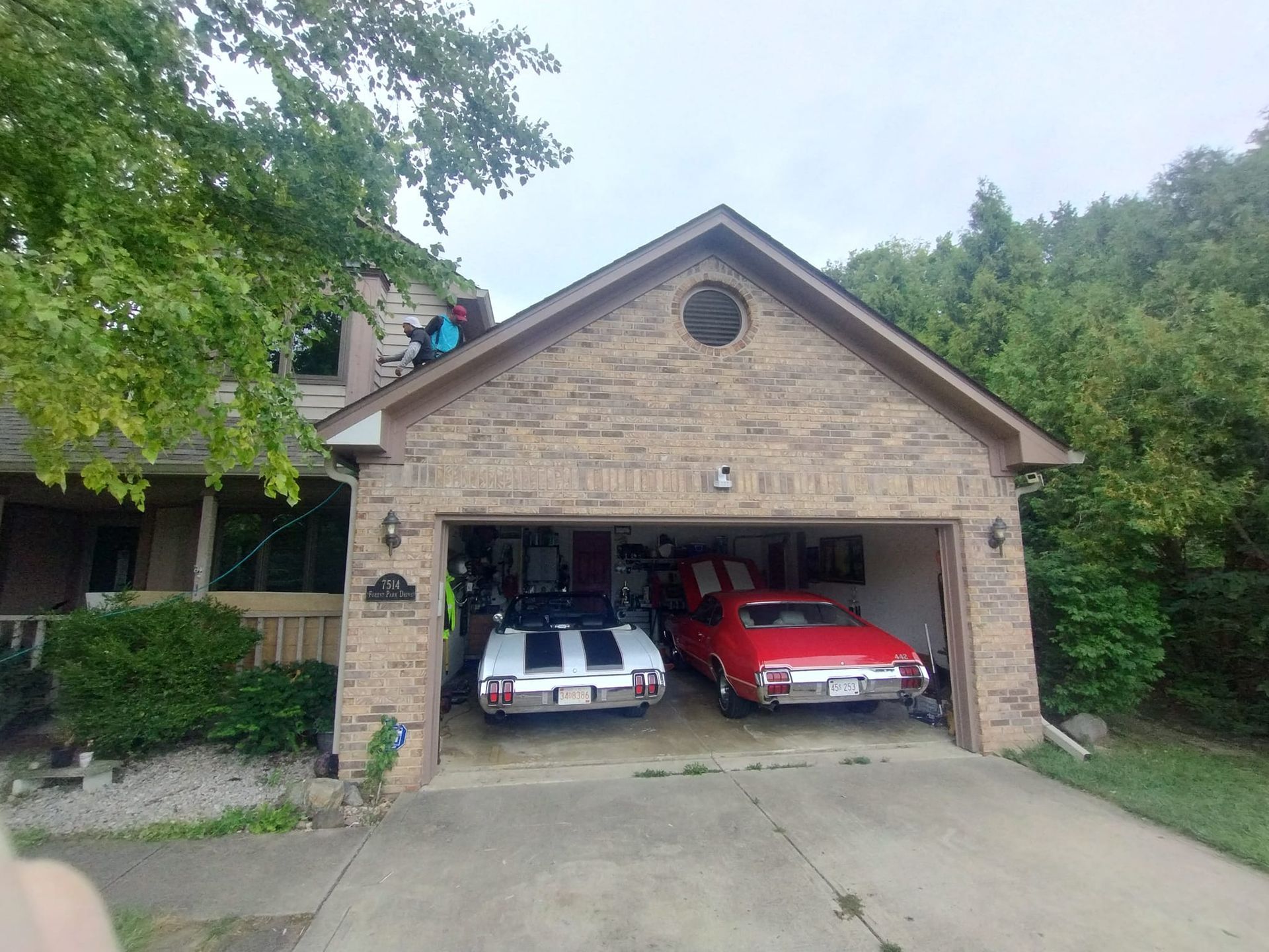 Two cars are parked in a garage in front of a house.