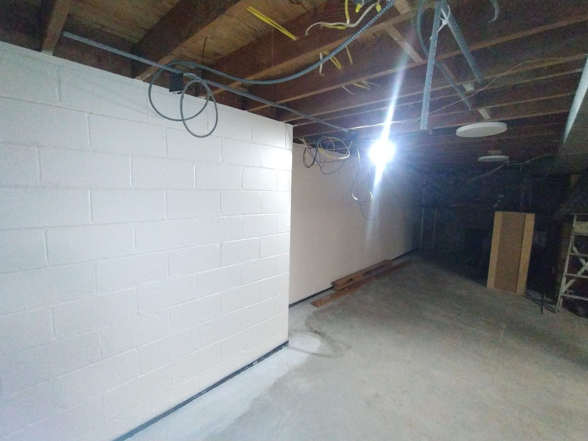A basement with white brick walls and a wooden ceiling.