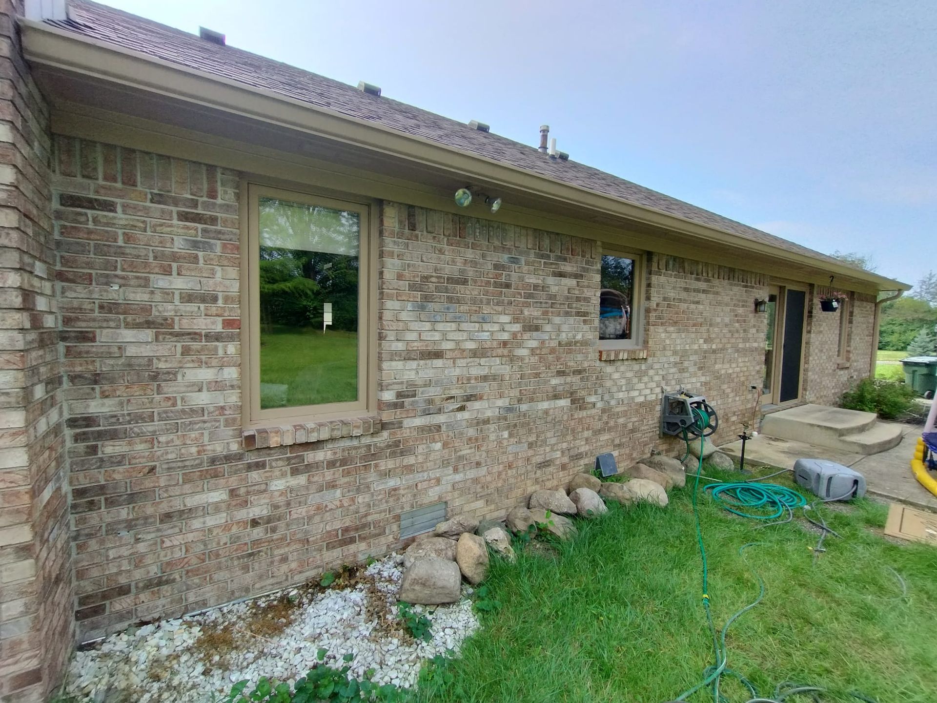 A brick house with a lot of windows and a hose in front of it.