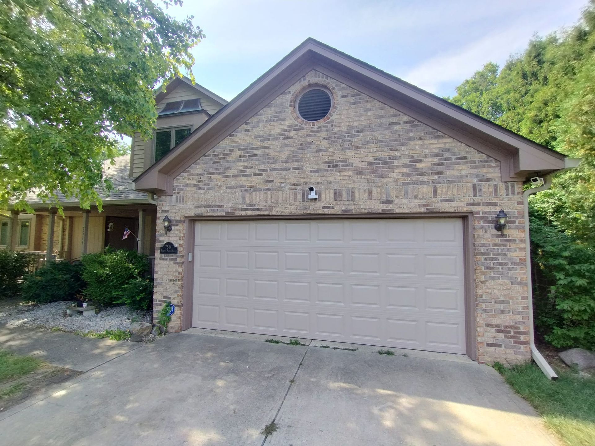A brick house with a large garage door and a driveway.