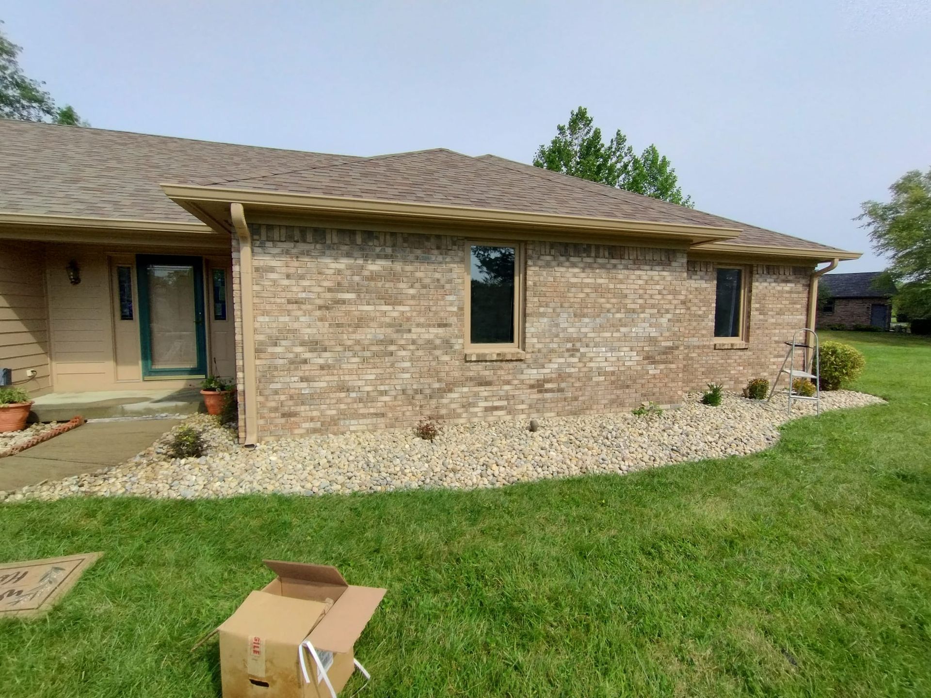 A cardboard box is sitting in front of a brick house.