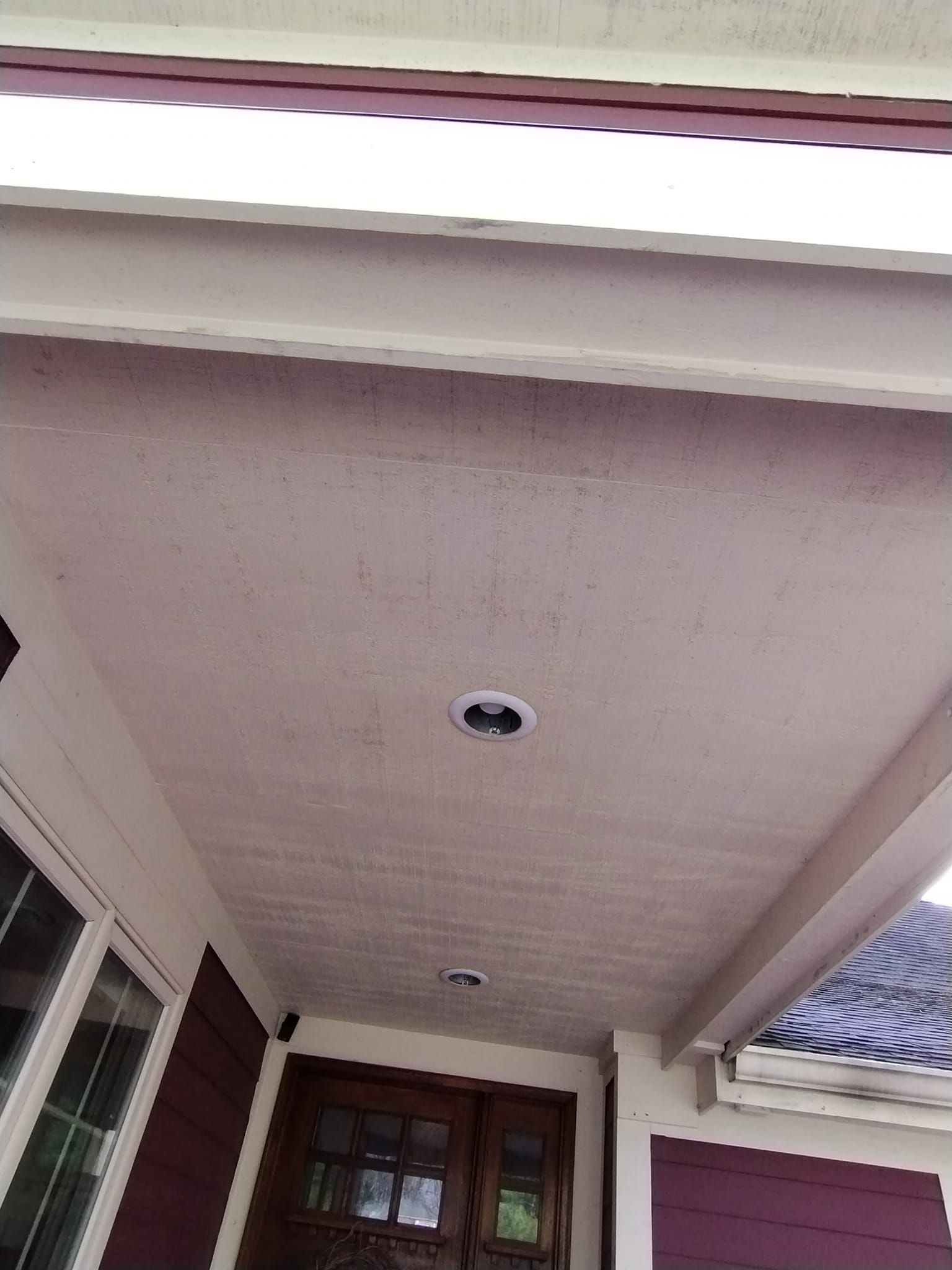 The ceiling of the porch of a house with a purple door.