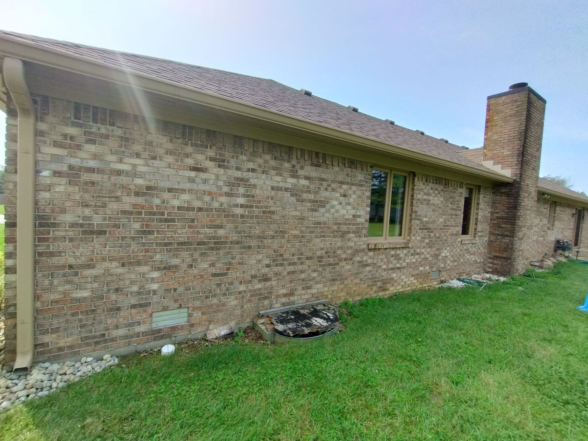 A brick house with a lot of windows and a chimney in the backyard.
