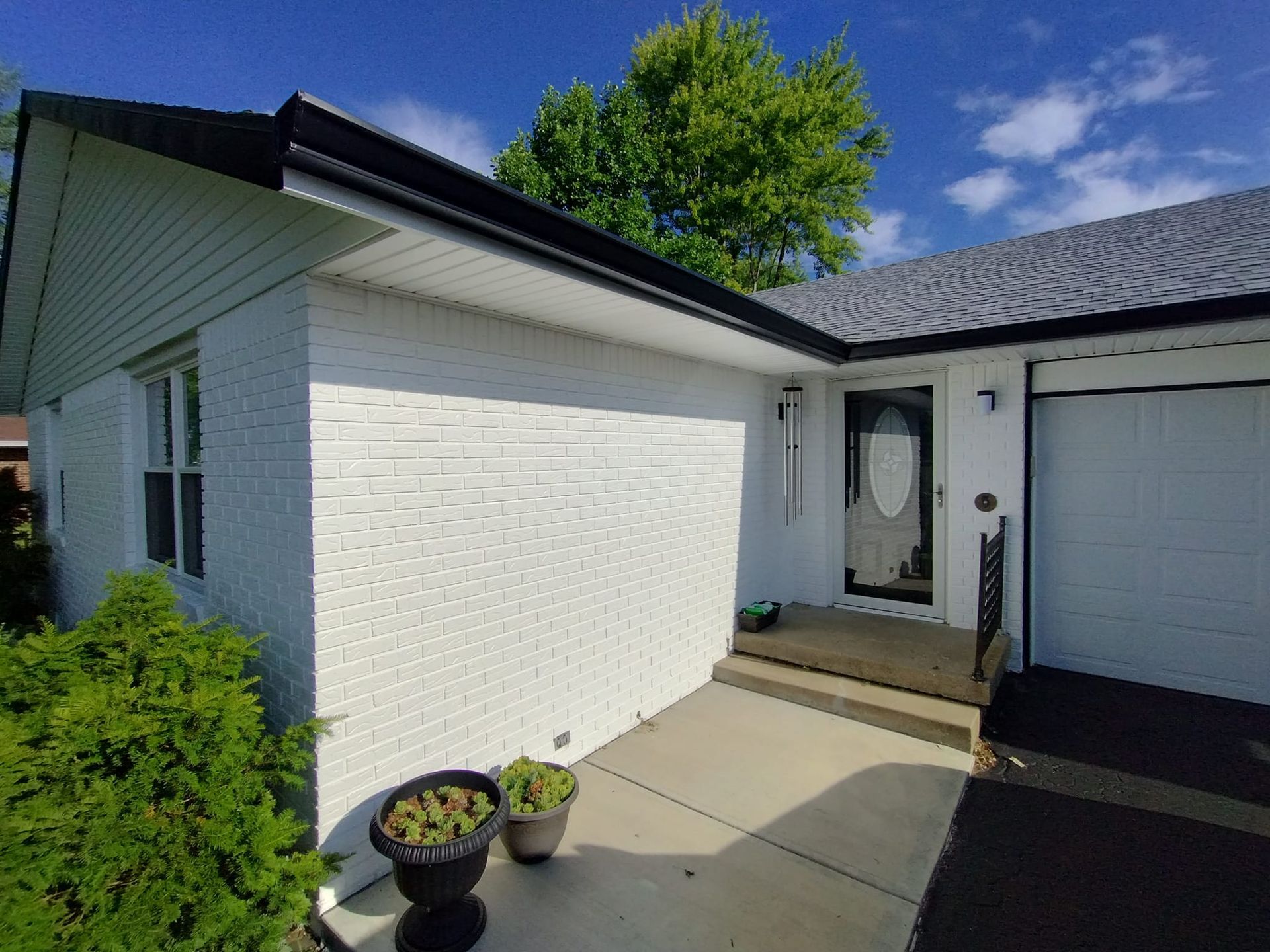 A white brick house with a garage and a porch.