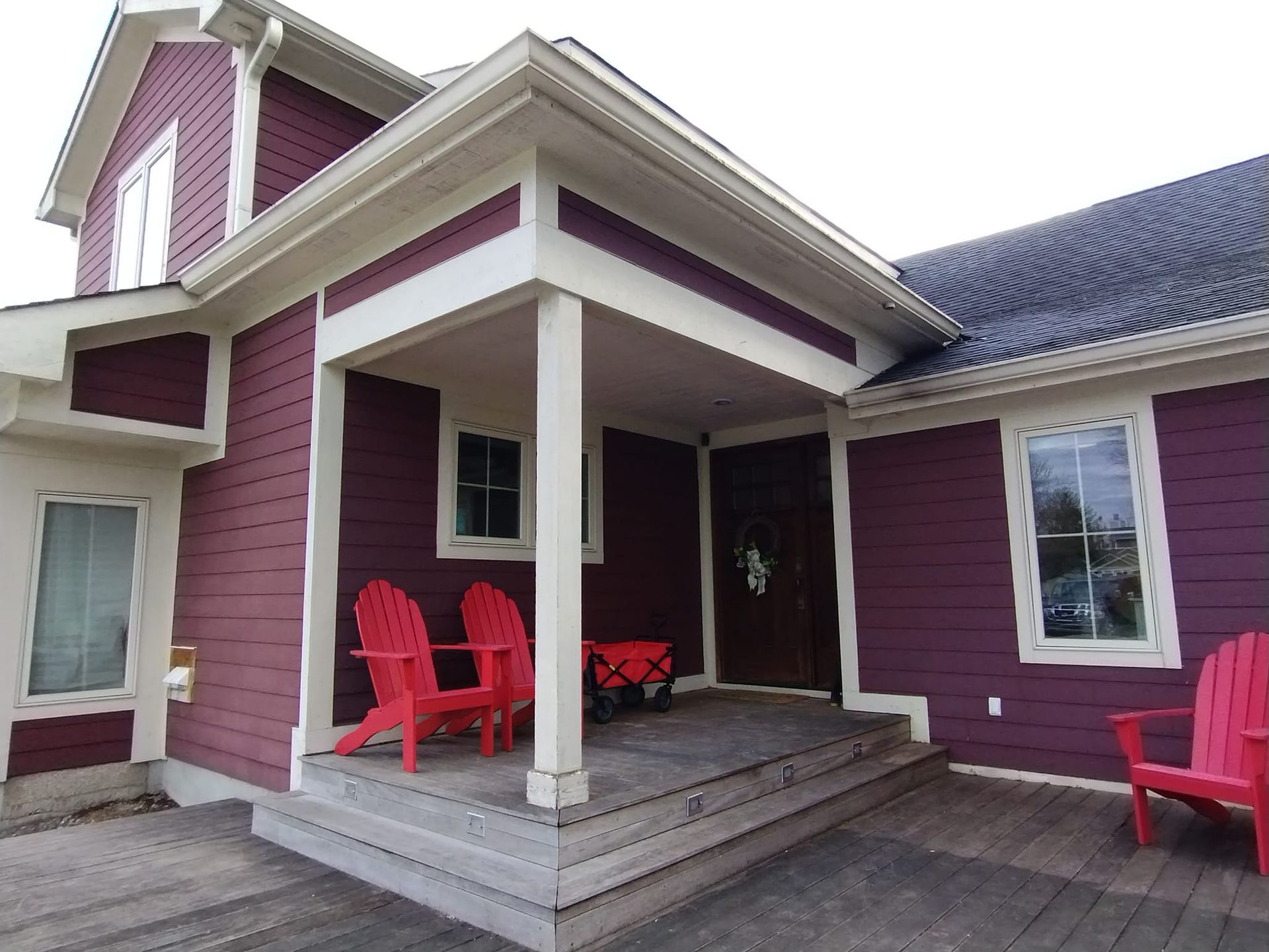 A purple house with red chairs on the porch
