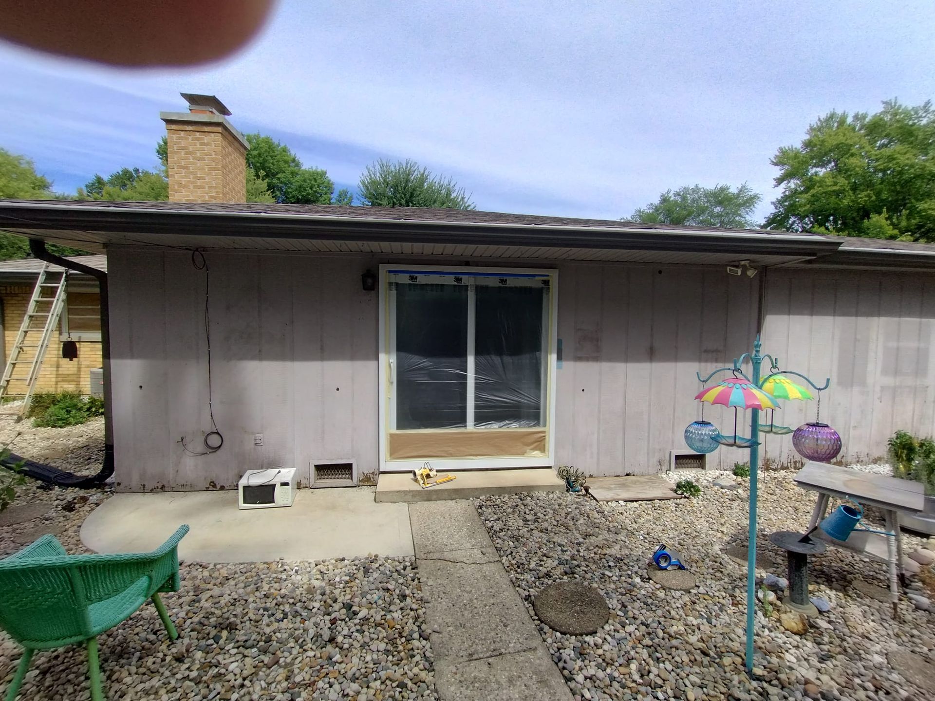 A house with a sliding glass door and a green chair in front of it.