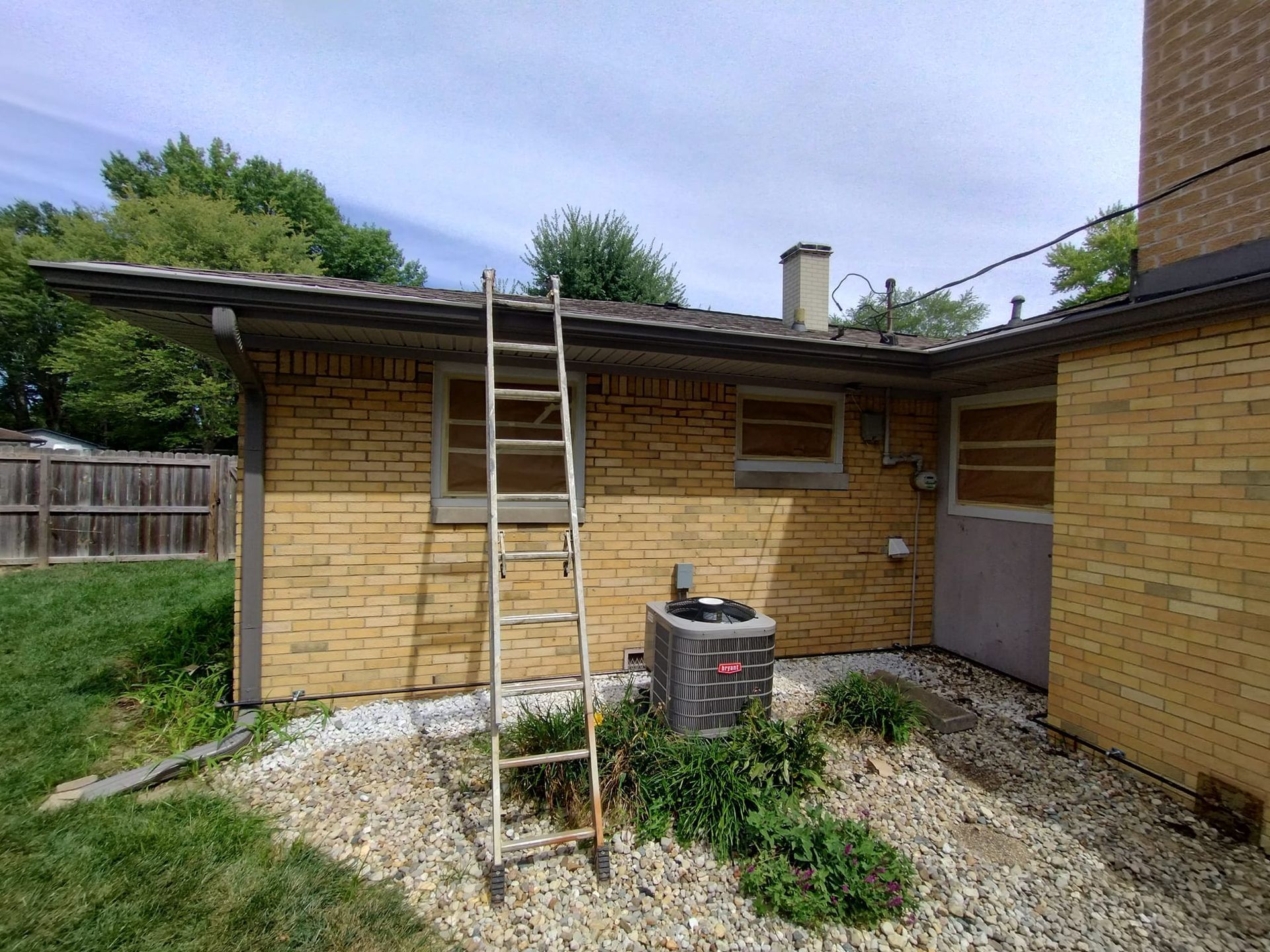 A ladder is sitting on the side of a brick house.