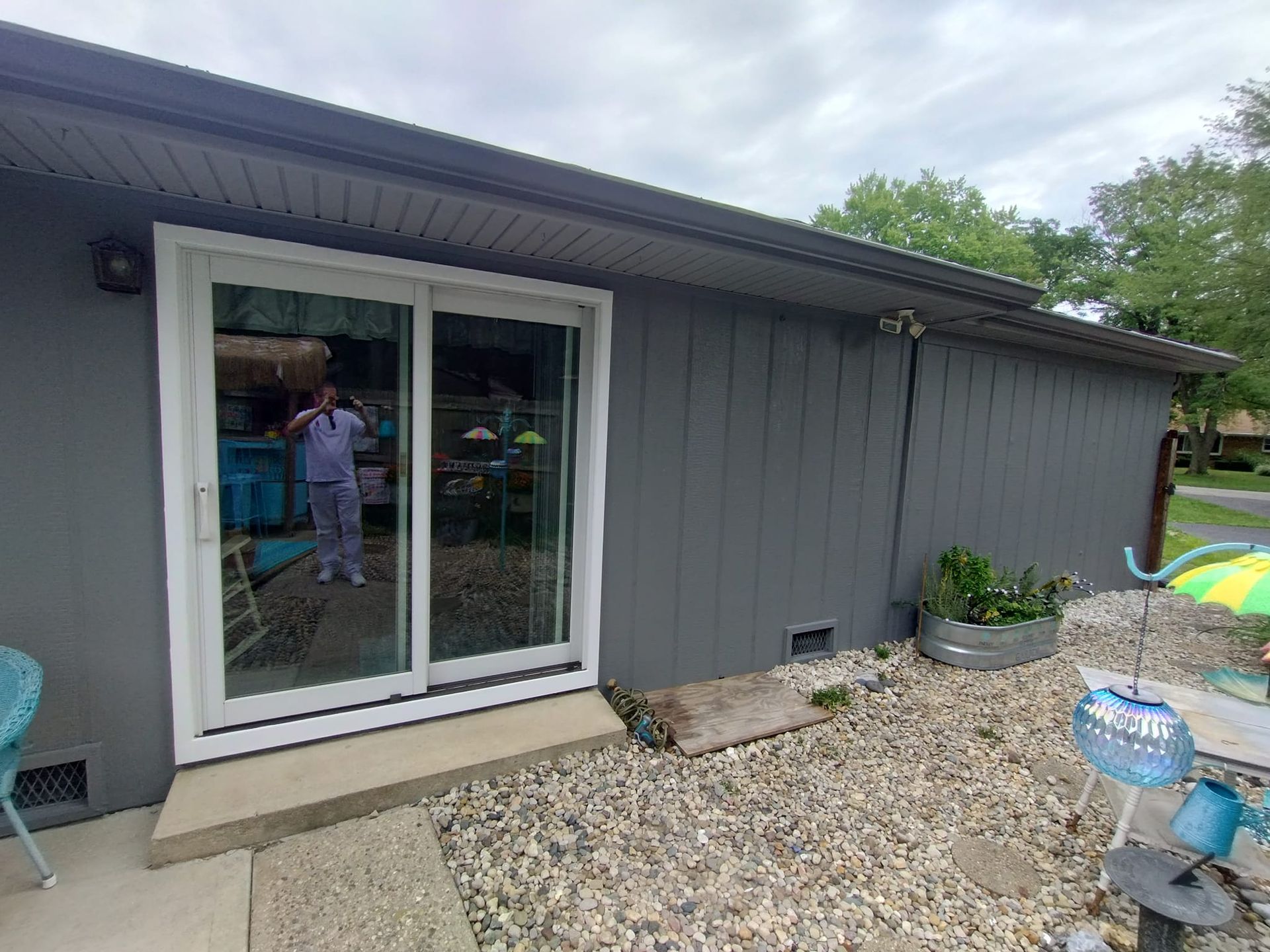 A man is standing in front of a house with a sliding glass door.