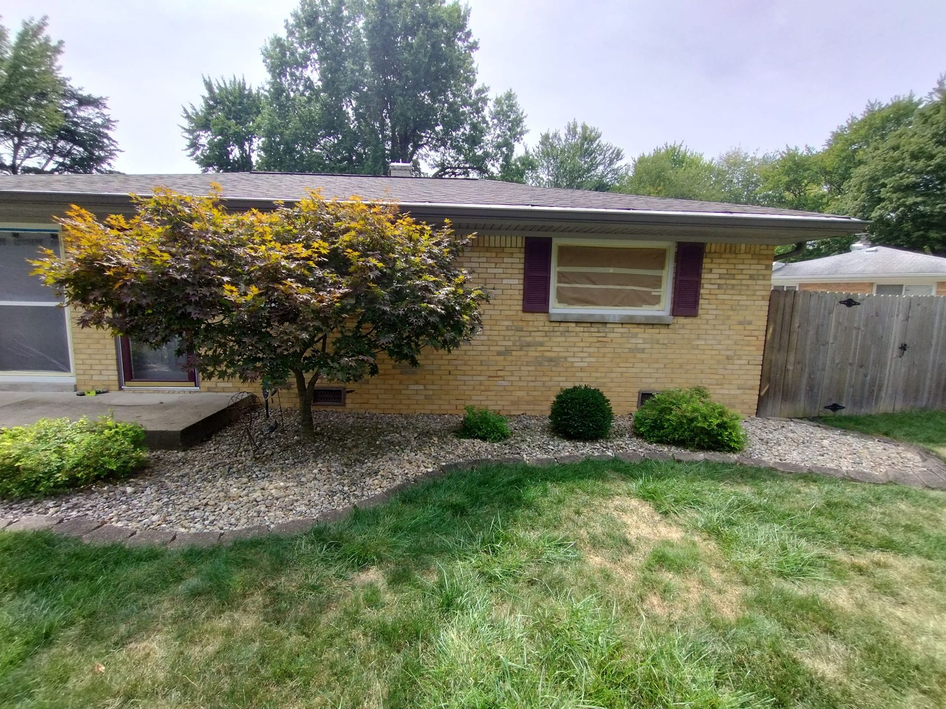 A brick house with a fence and a tree in front of it.