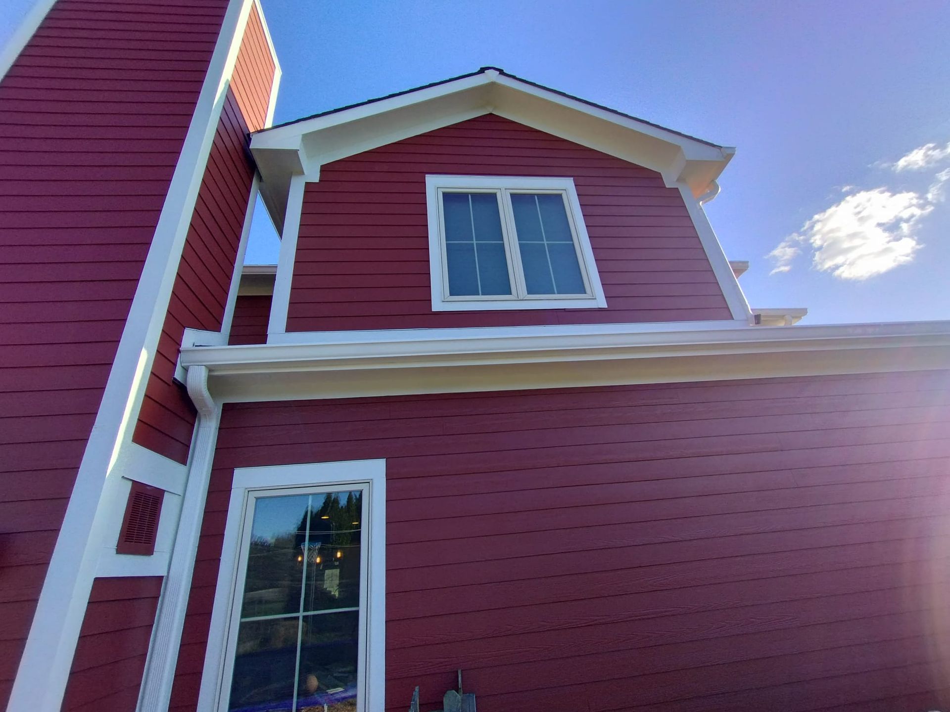 A red house with white trim and a blue sky in the background
