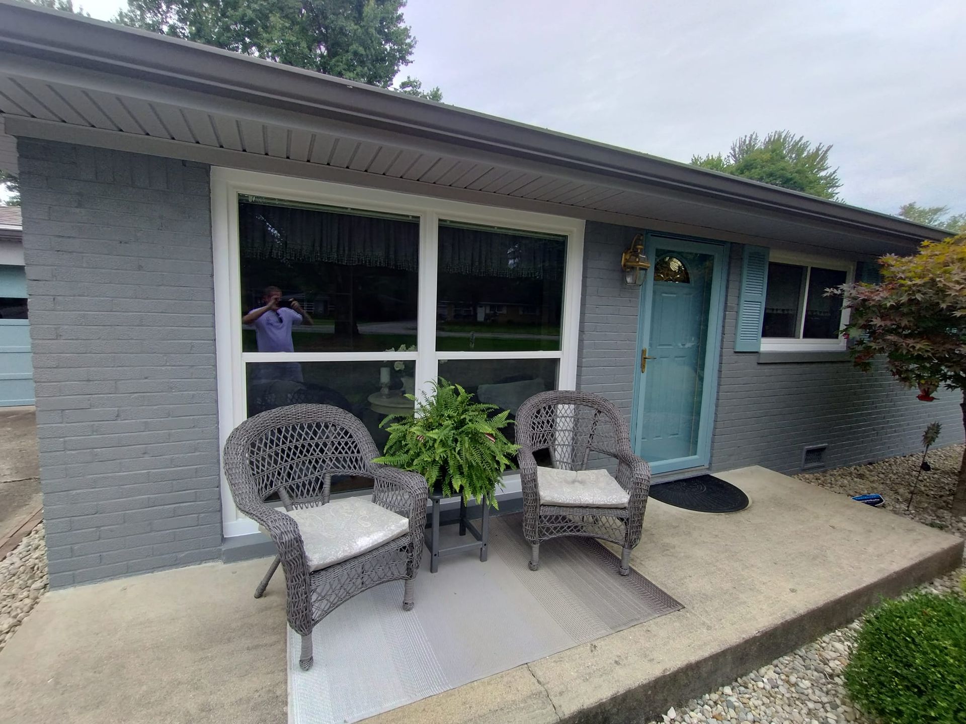 A gray brick house with two chairs and a table in front of it.