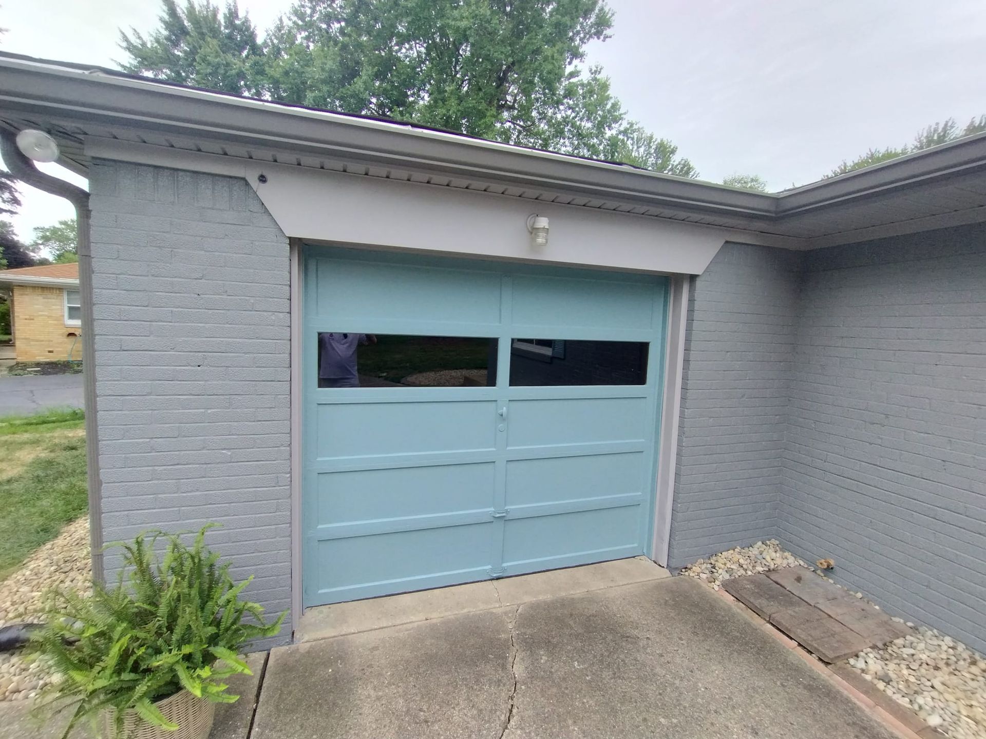 A blue garage door is on the side of a house.