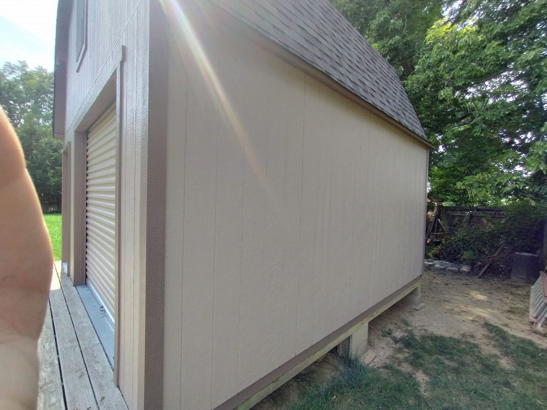 A person is standing in front of a shed with a garage door.
