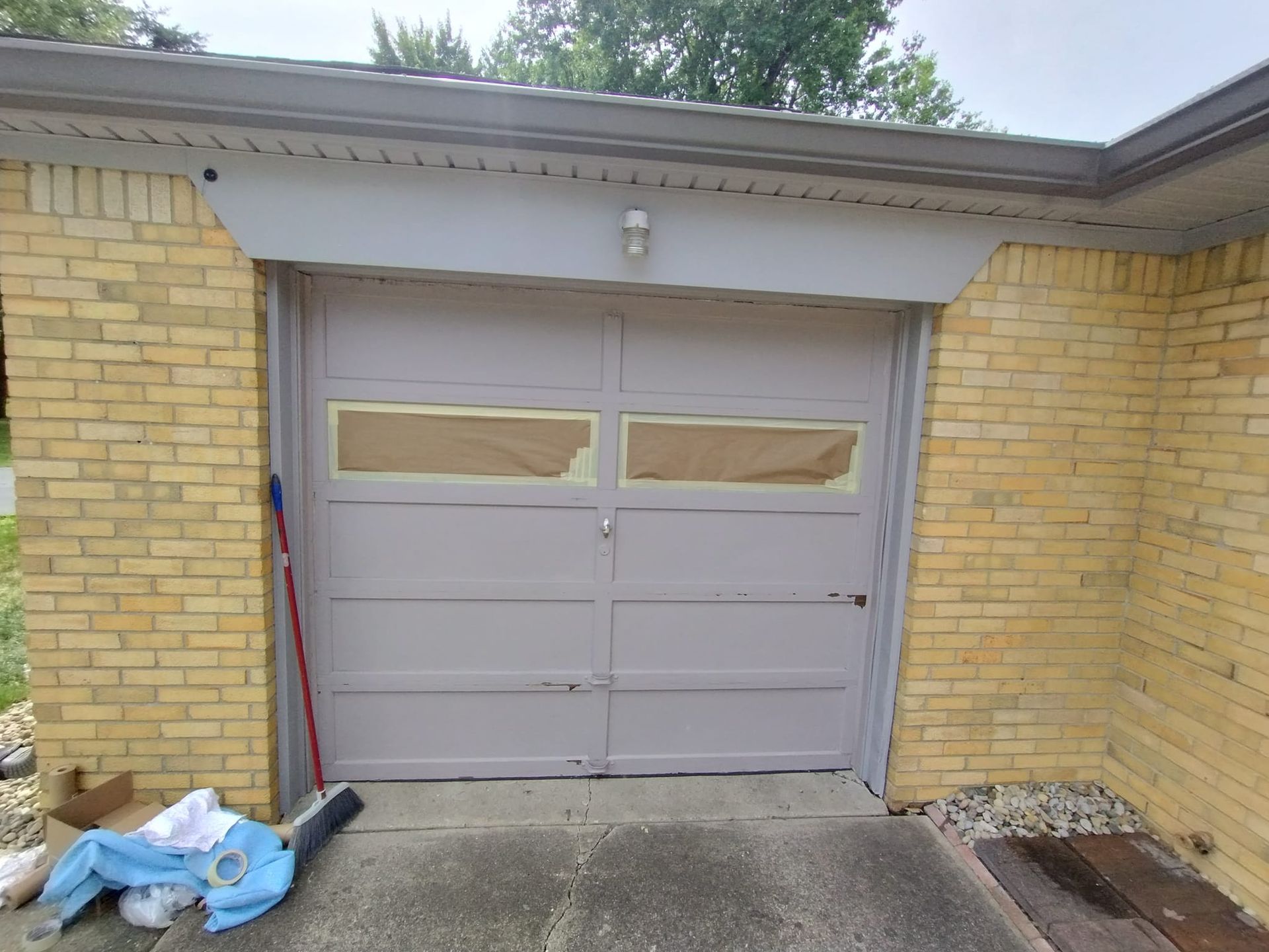 A gray garage door is sitting on the side of a brick building.