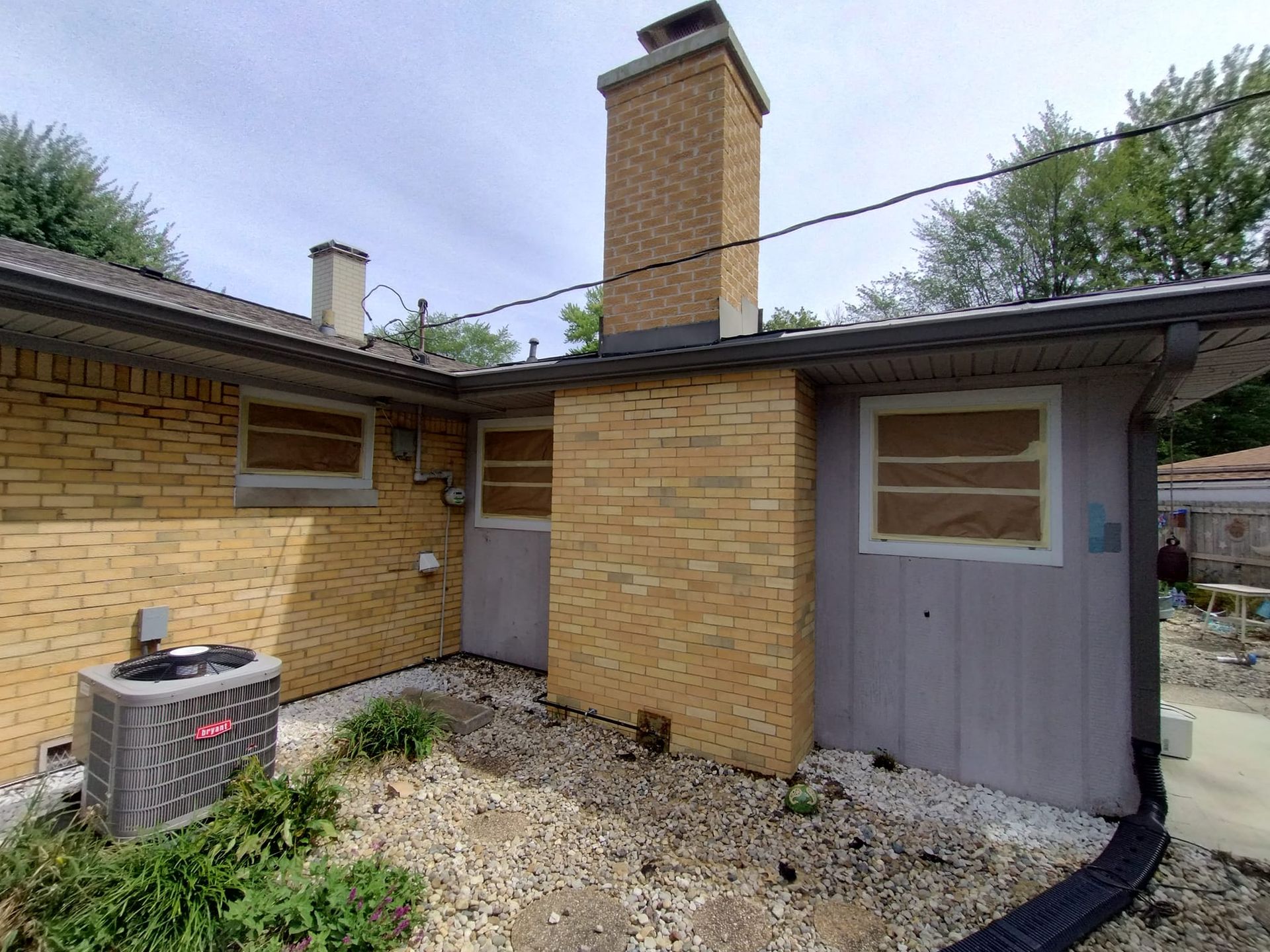 The back of a brick house with a chimney and air conditioner.
