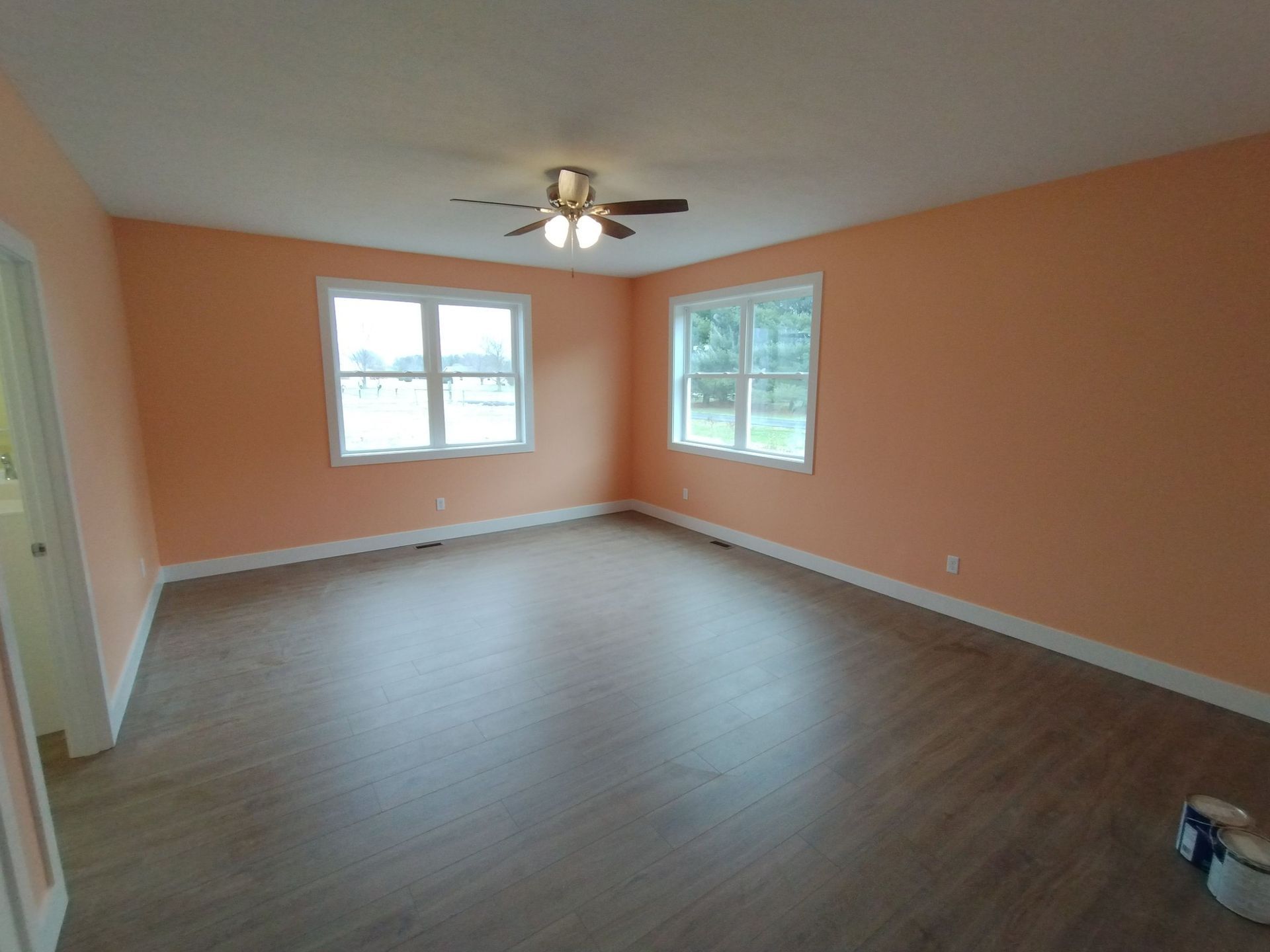 An empty living room with orange walls and a ceiling fan.