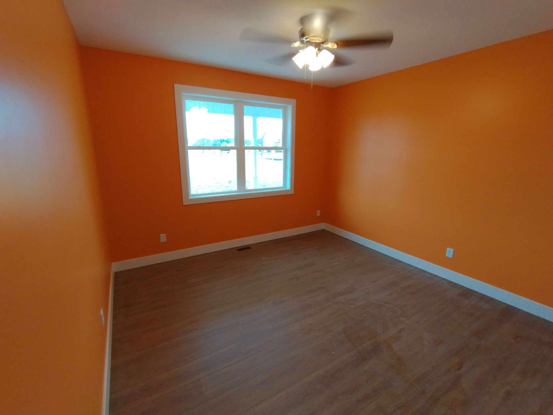 An empty room with orange walls and a ceiling fan