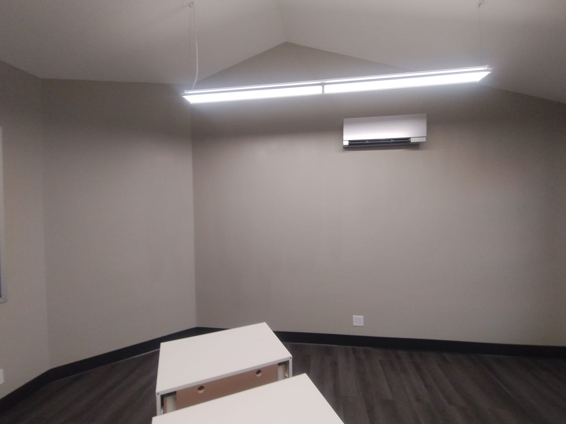 An empty room with two tables and a ceiling fan