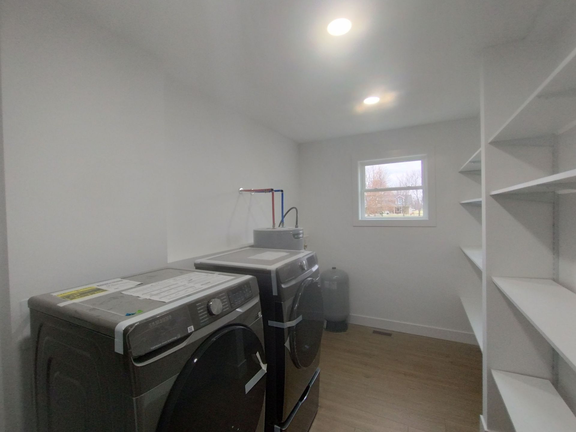 A laundry room with a washer and dryer and shelves.