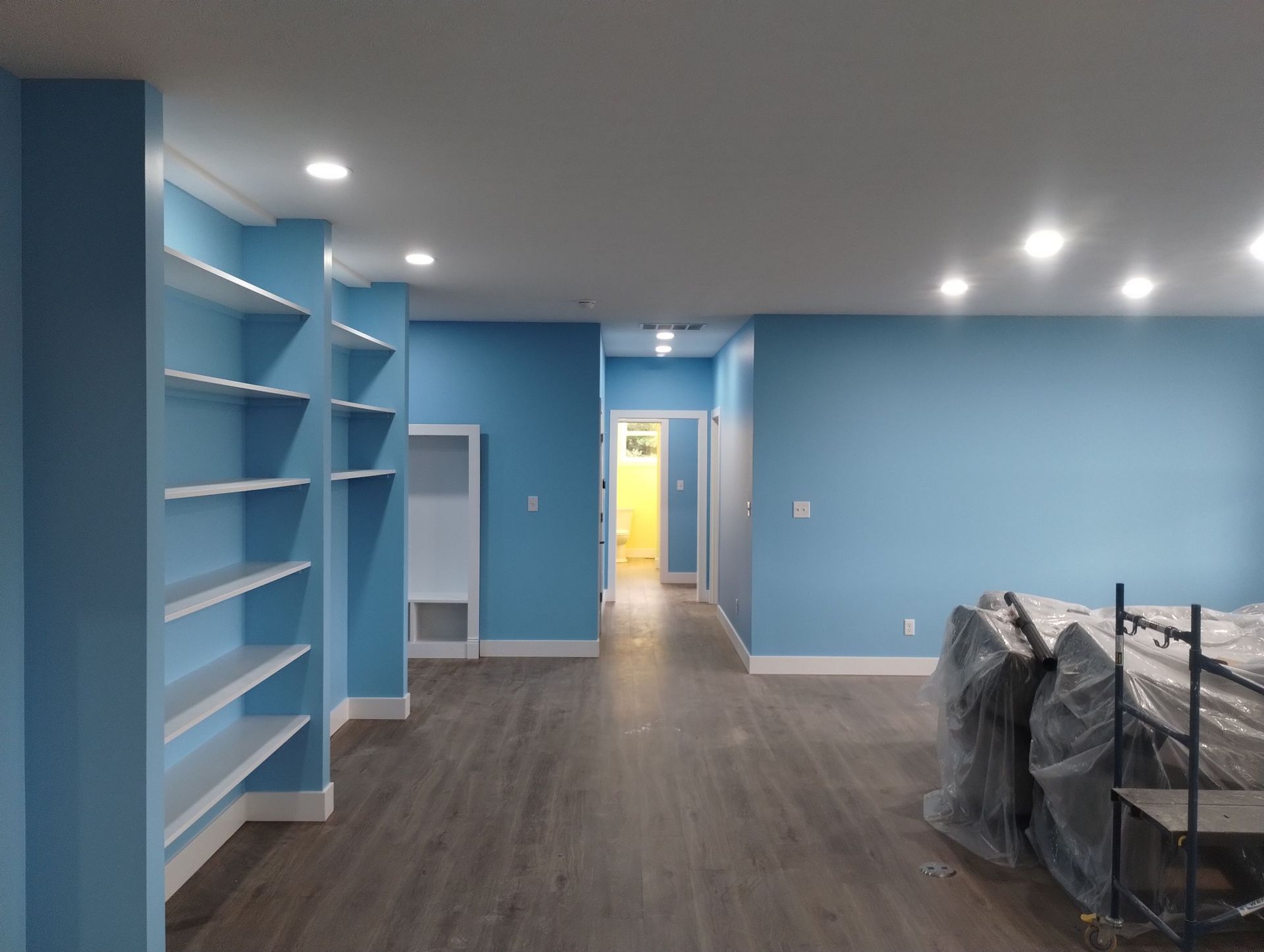 An empty room with blue walls and white shelves