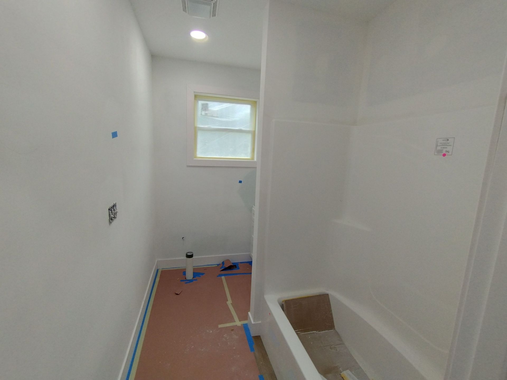 A bathroom under construction with a bathtub and a window.