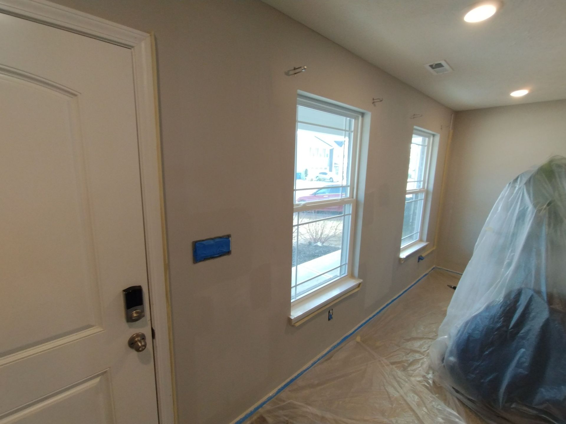 A room with a door and three windows is being painted.