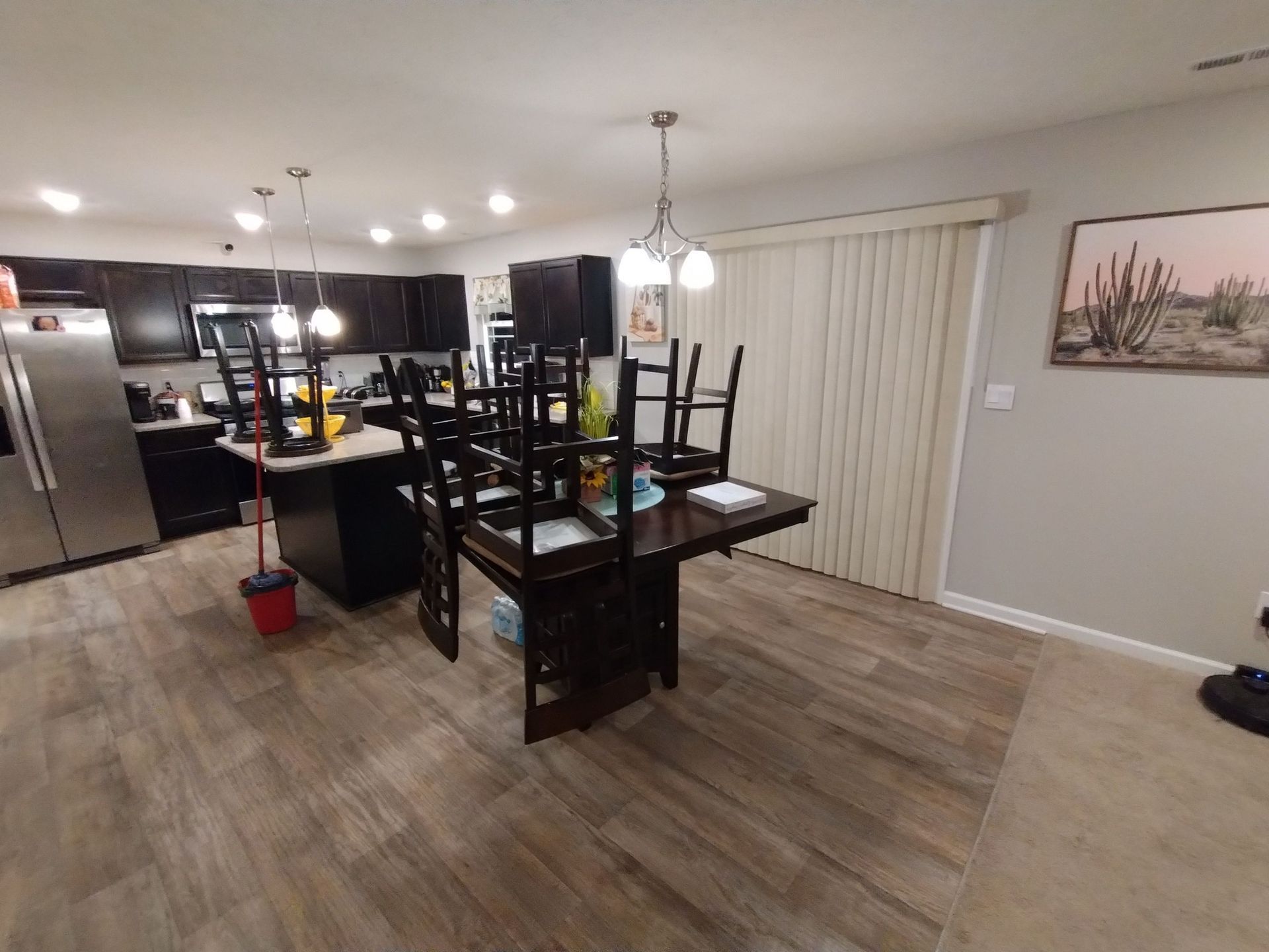 A dining room table with chairs stacked on top of it in a kitchen.