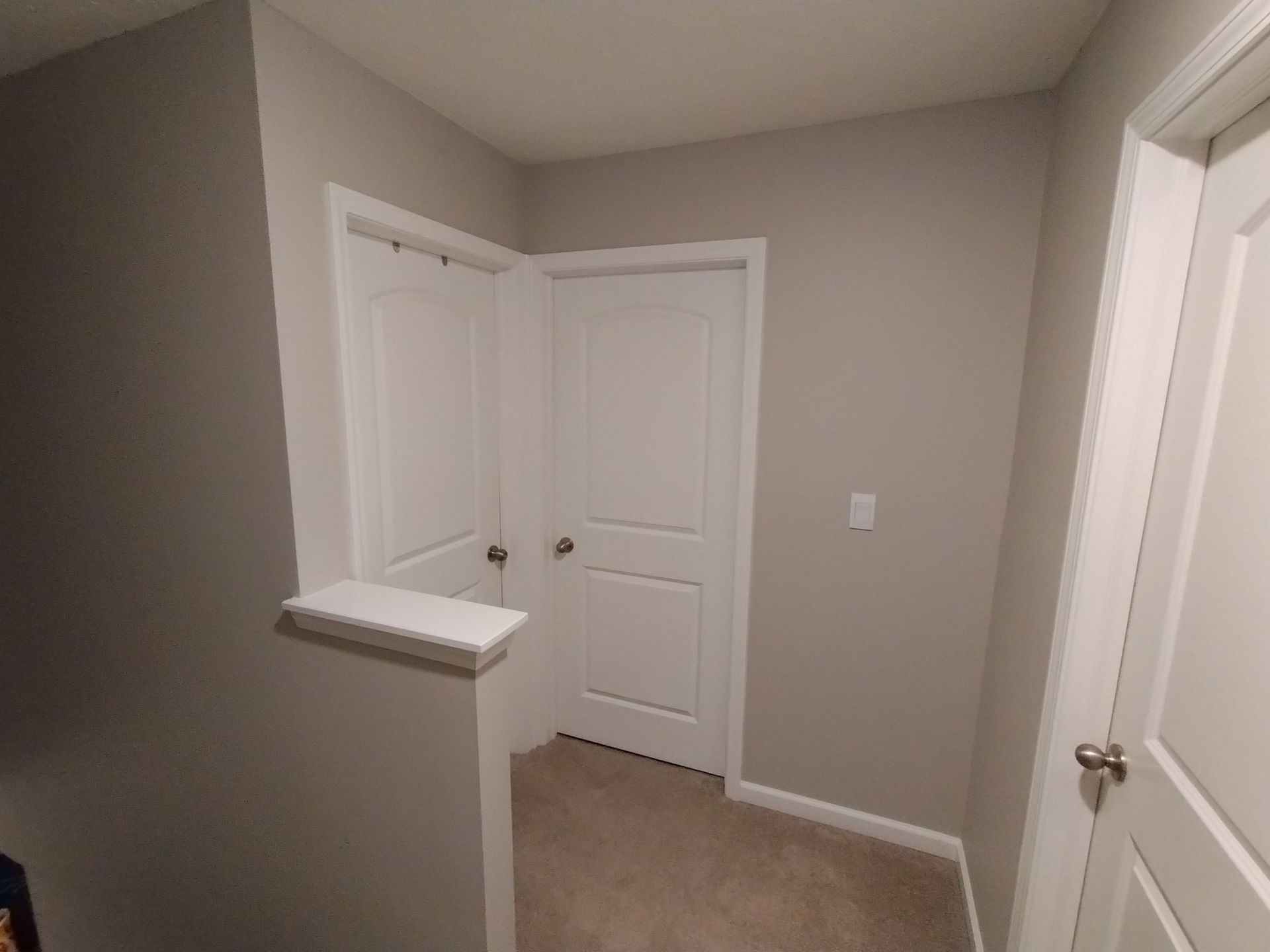 A hallway with two doors and a staircase in a house.