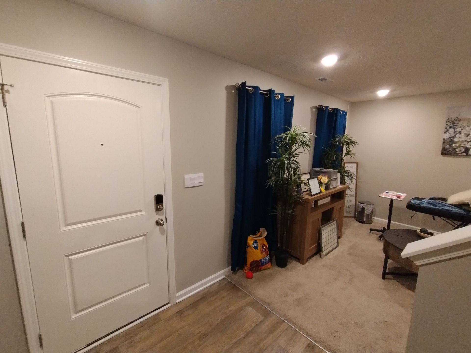 A hallway in a house with a door and a desk.