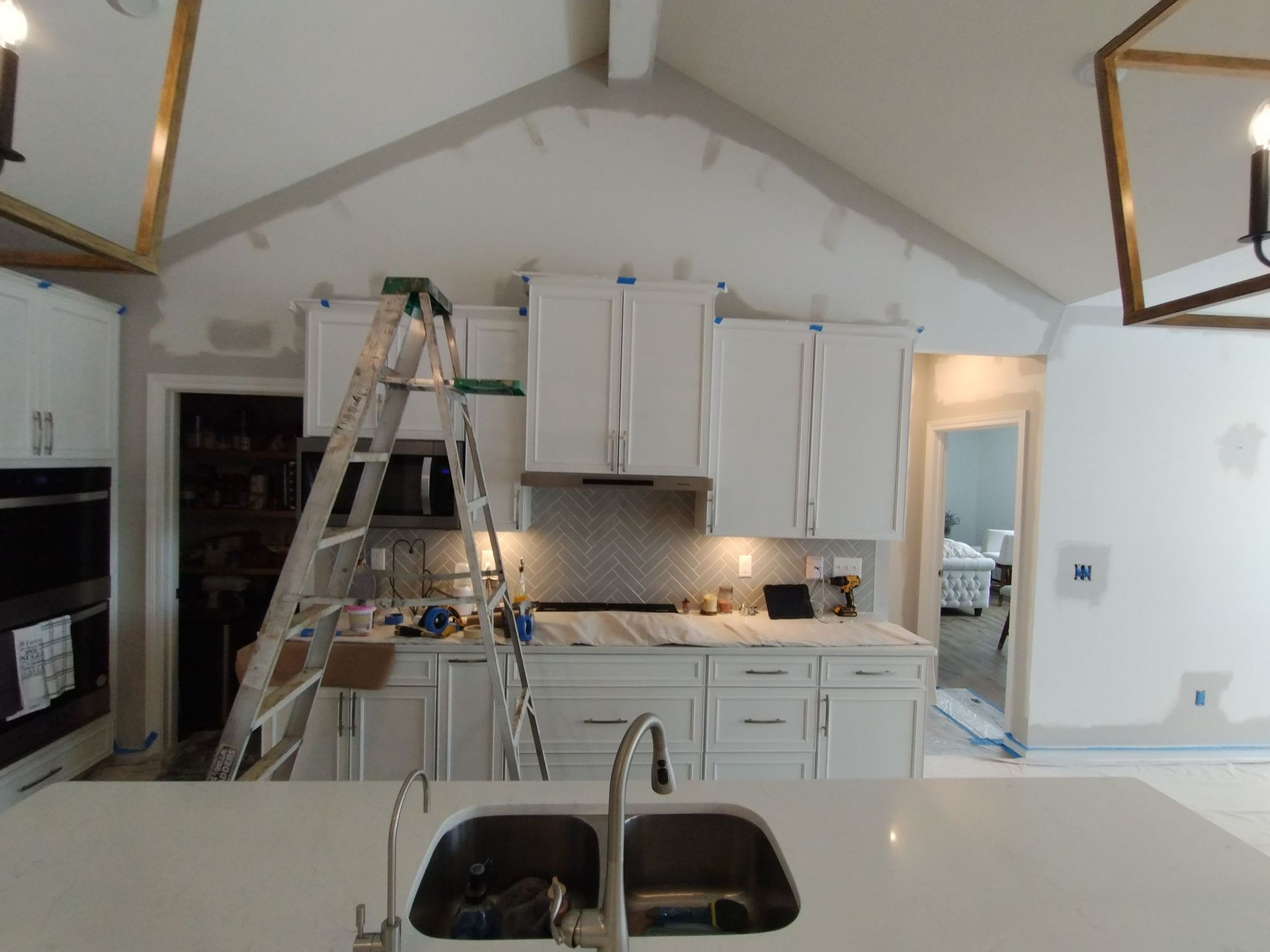 A kitchen with white cabinets and a sink and a ladder.