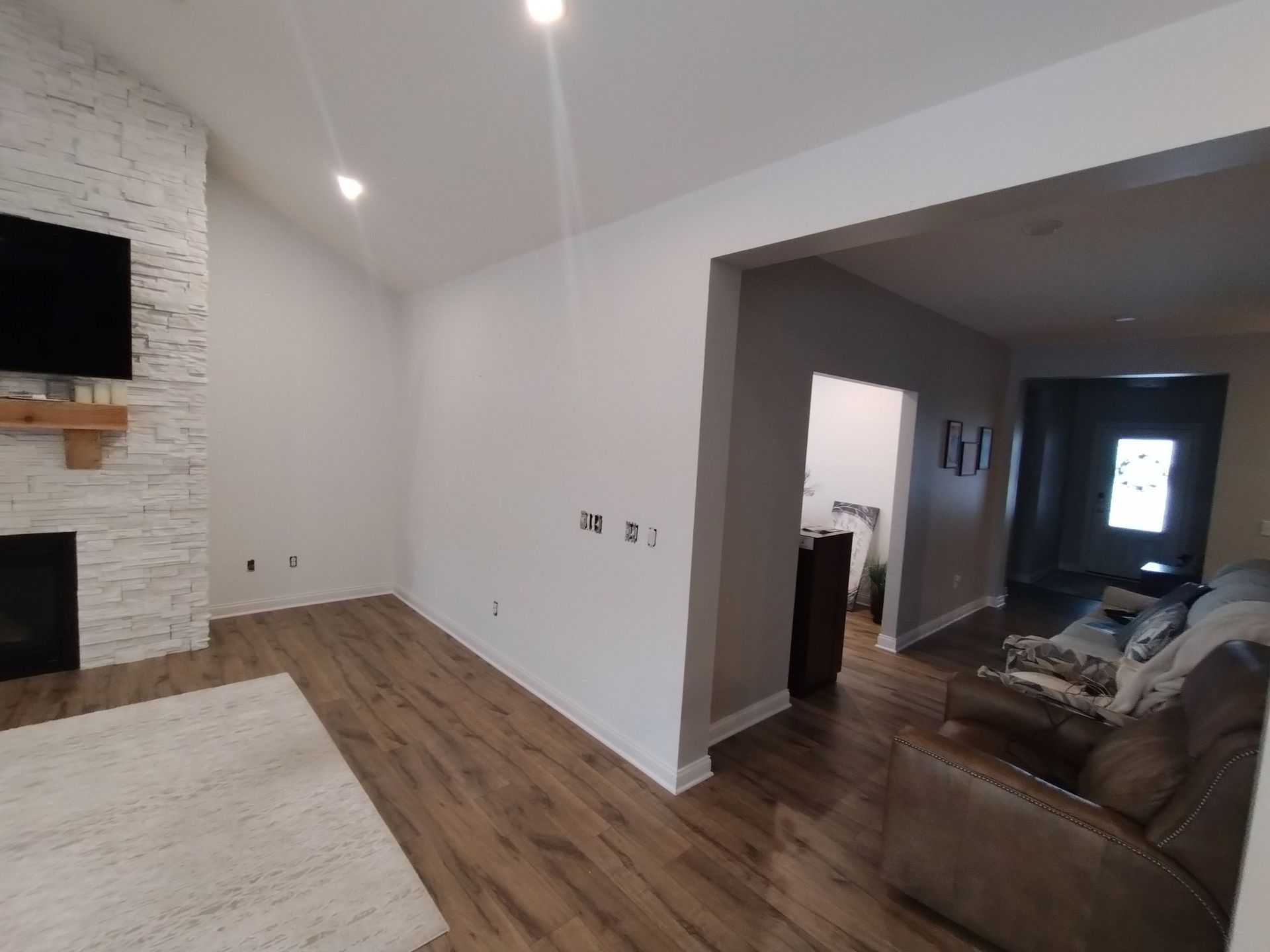 A living room with a couch , chair , television and fireplace.