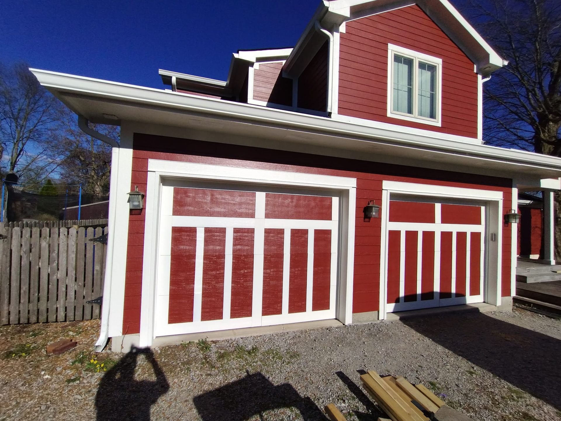 A red house with two garage doors and a white trim