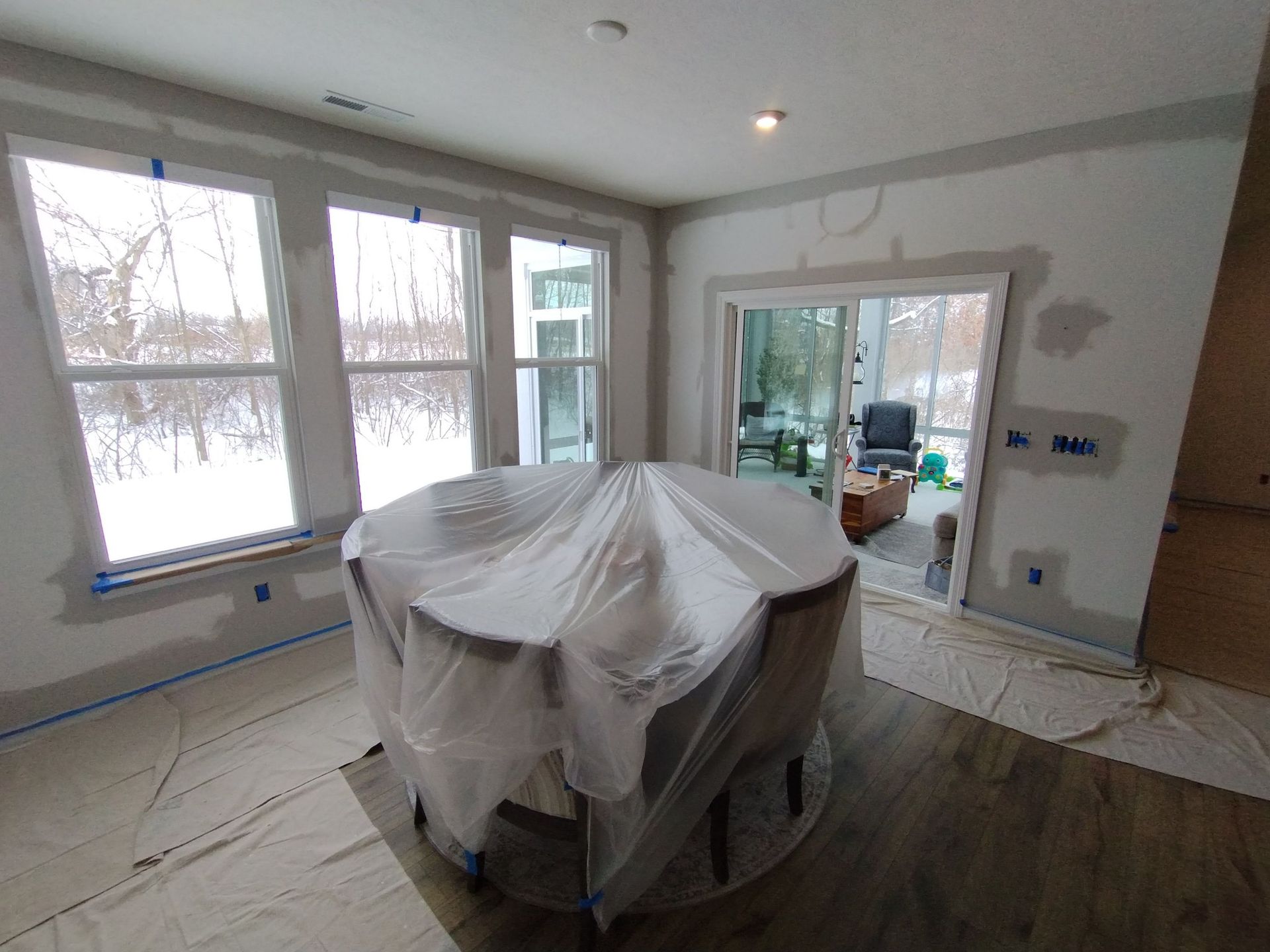 A room with a table and chairs wrapped in plastic.