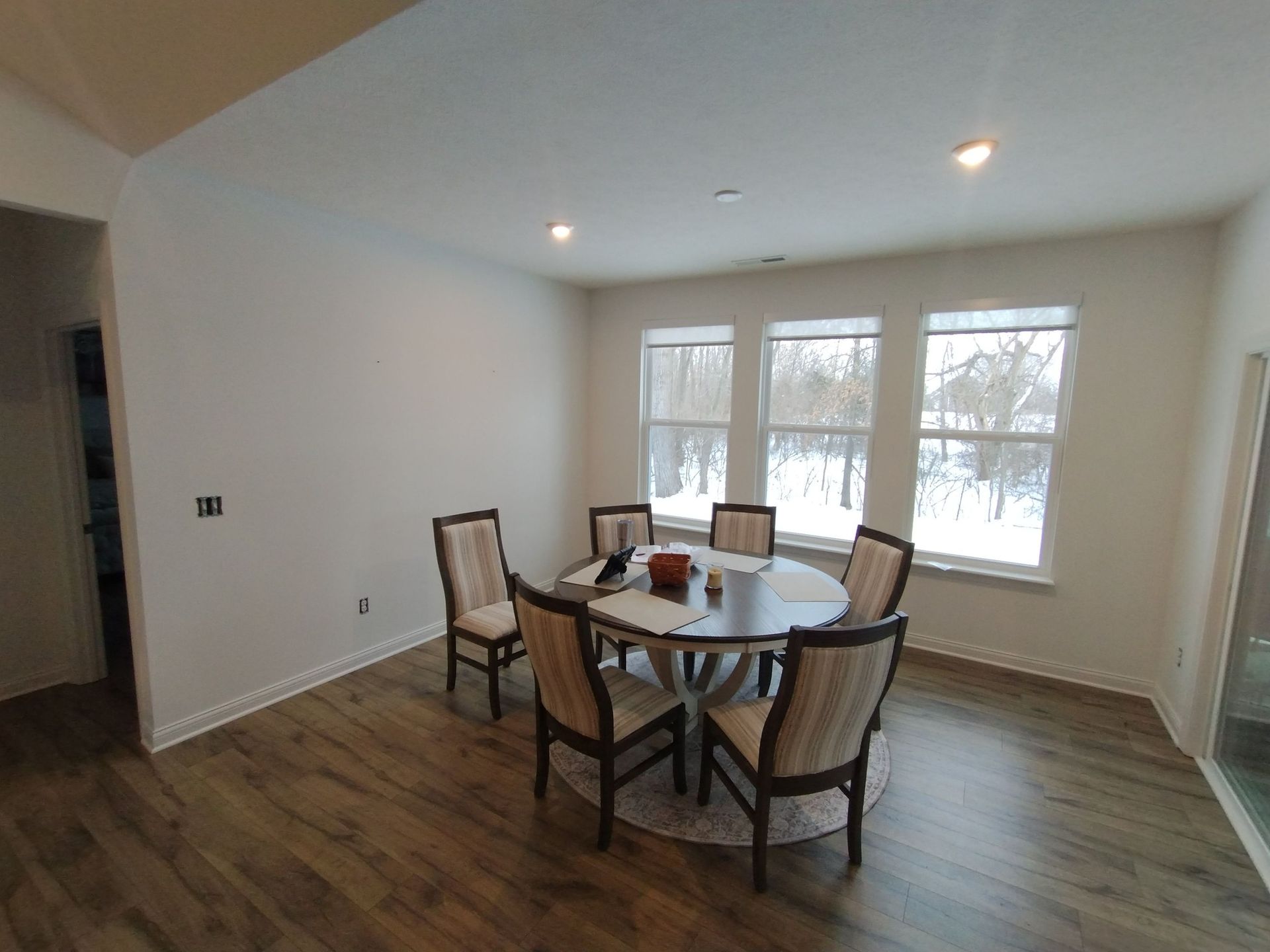 A dining room with a round table and chairs and a lot of windows.