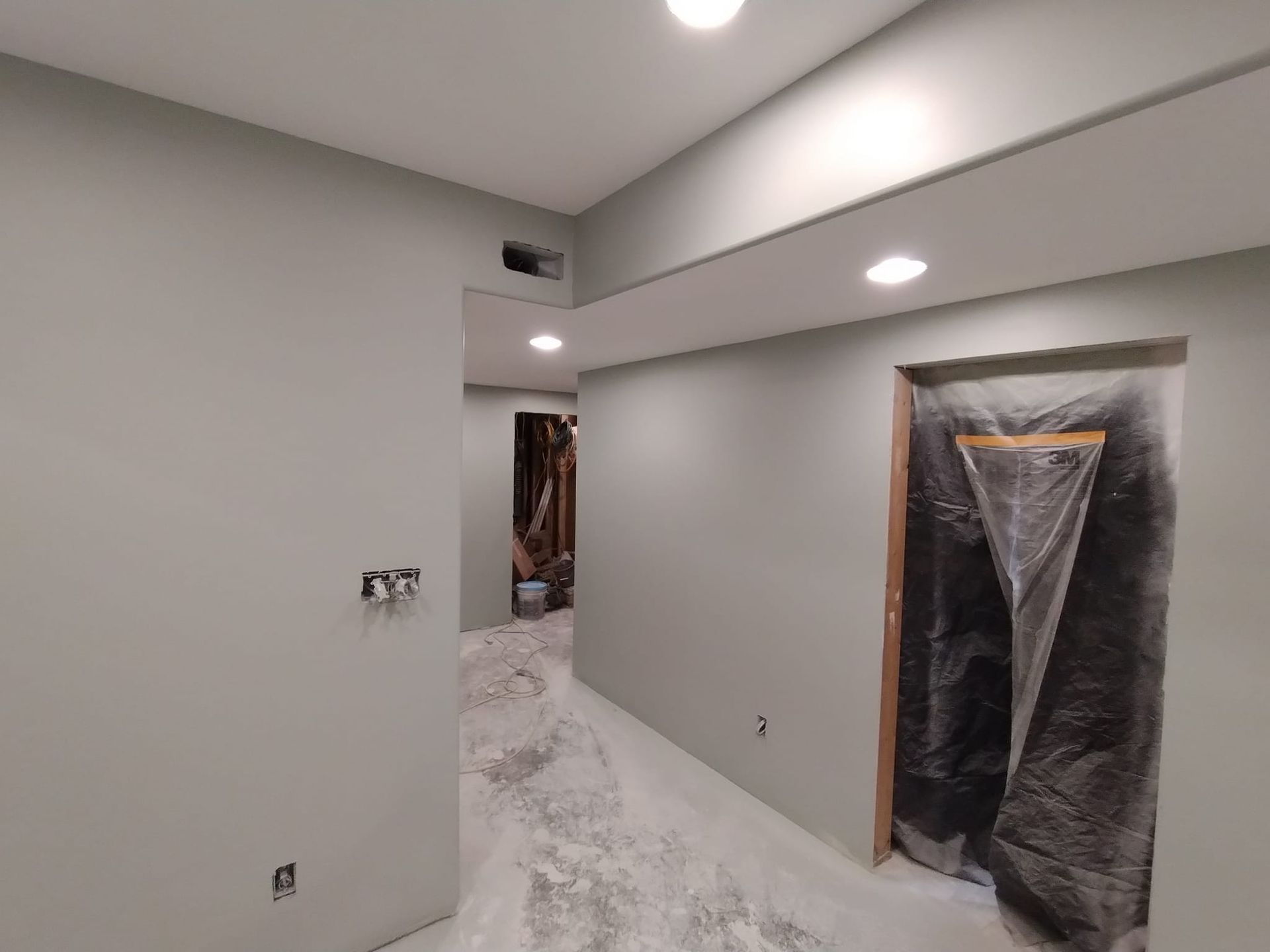 A hallway in a house under construction with a door covered in plastic.
