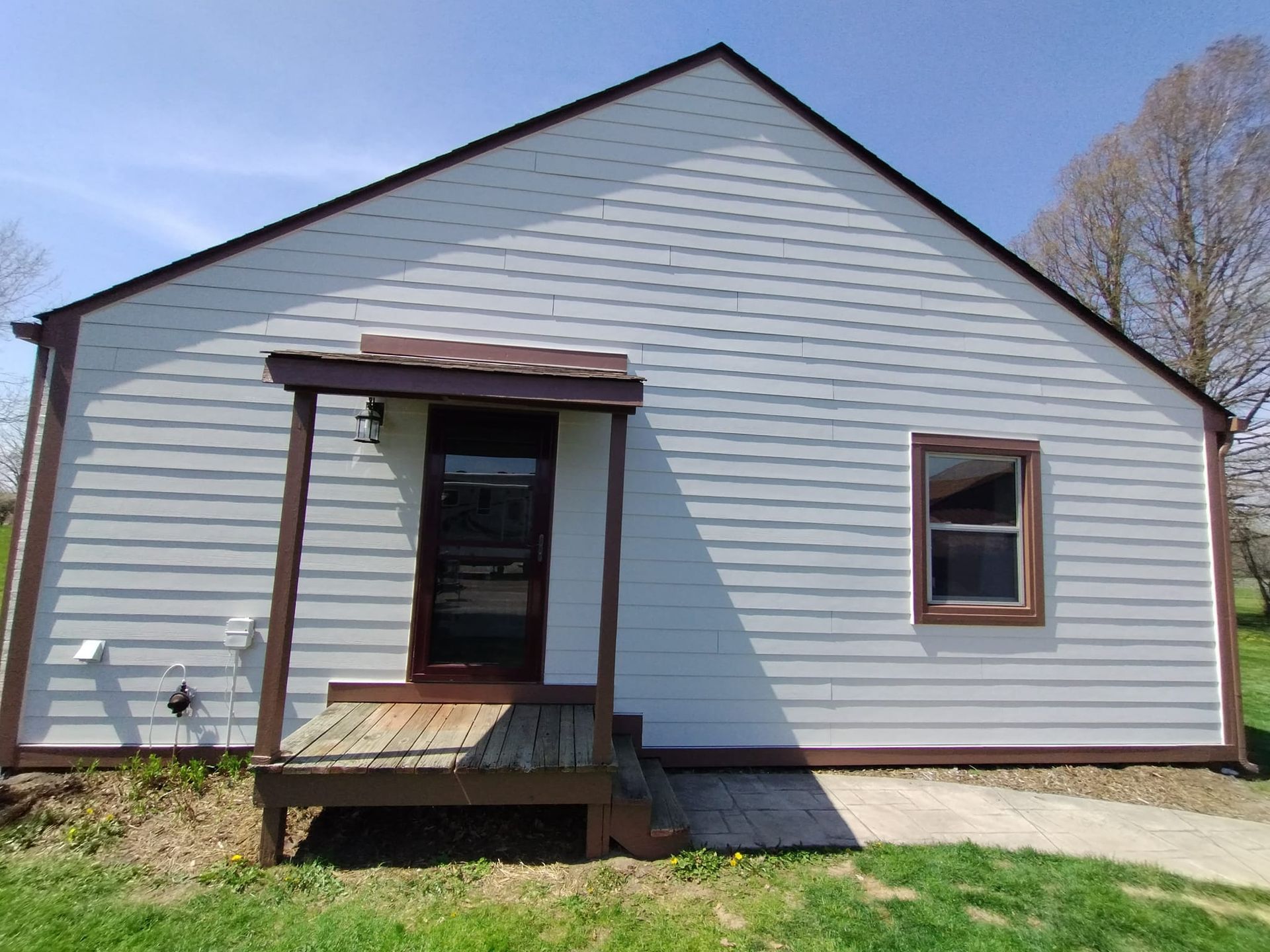 A small white house with a porch and stairs